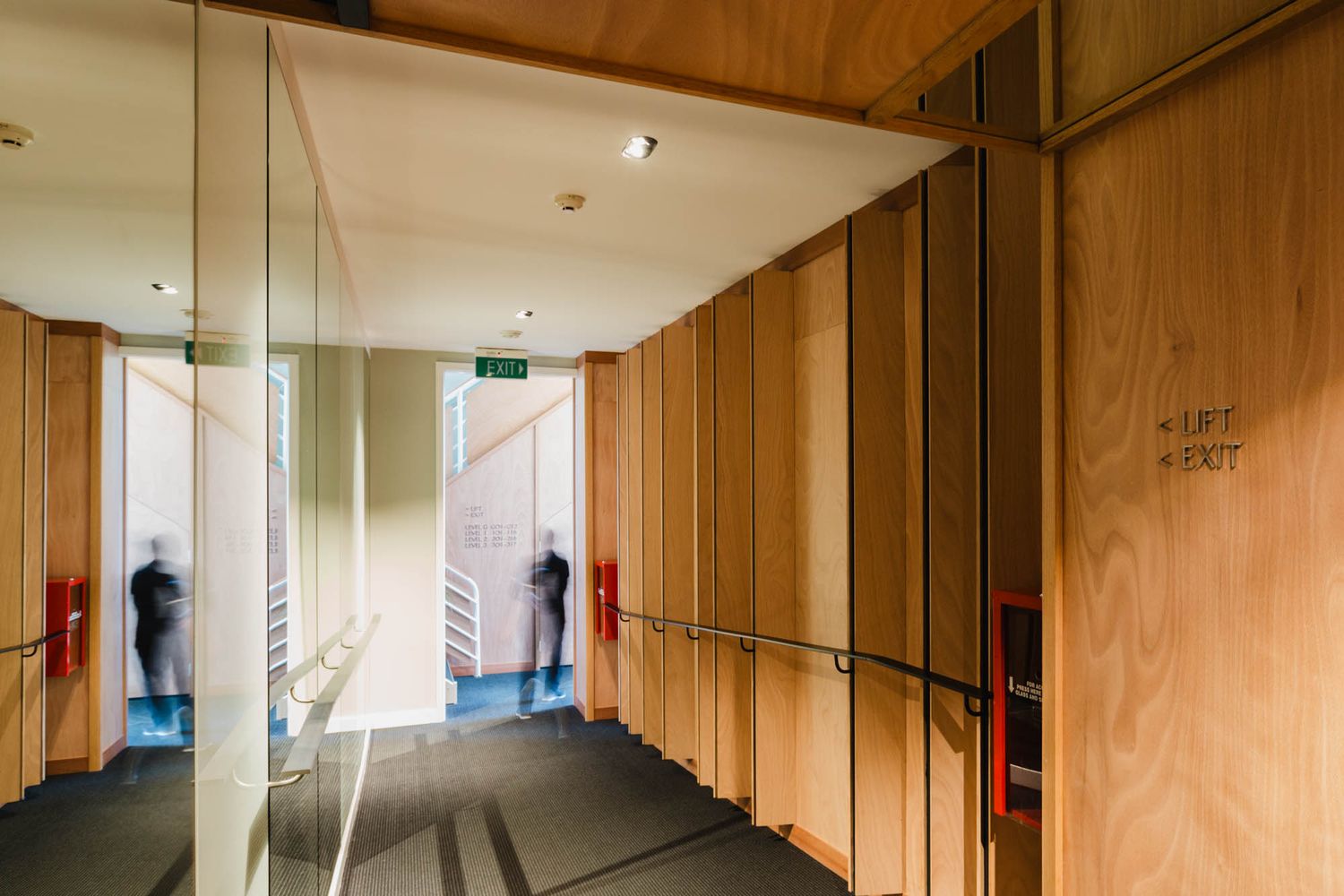 Long hallway in Gilmer Hotel with wooden paneling and recessed lighting creating warm interior ambiance.