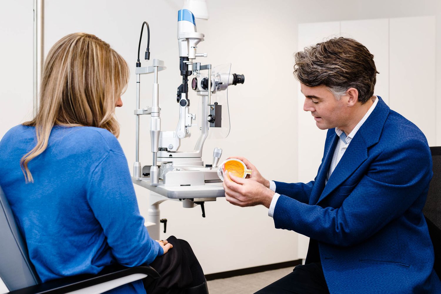 Eye doctor working with laboratory equipment in clinical setting.