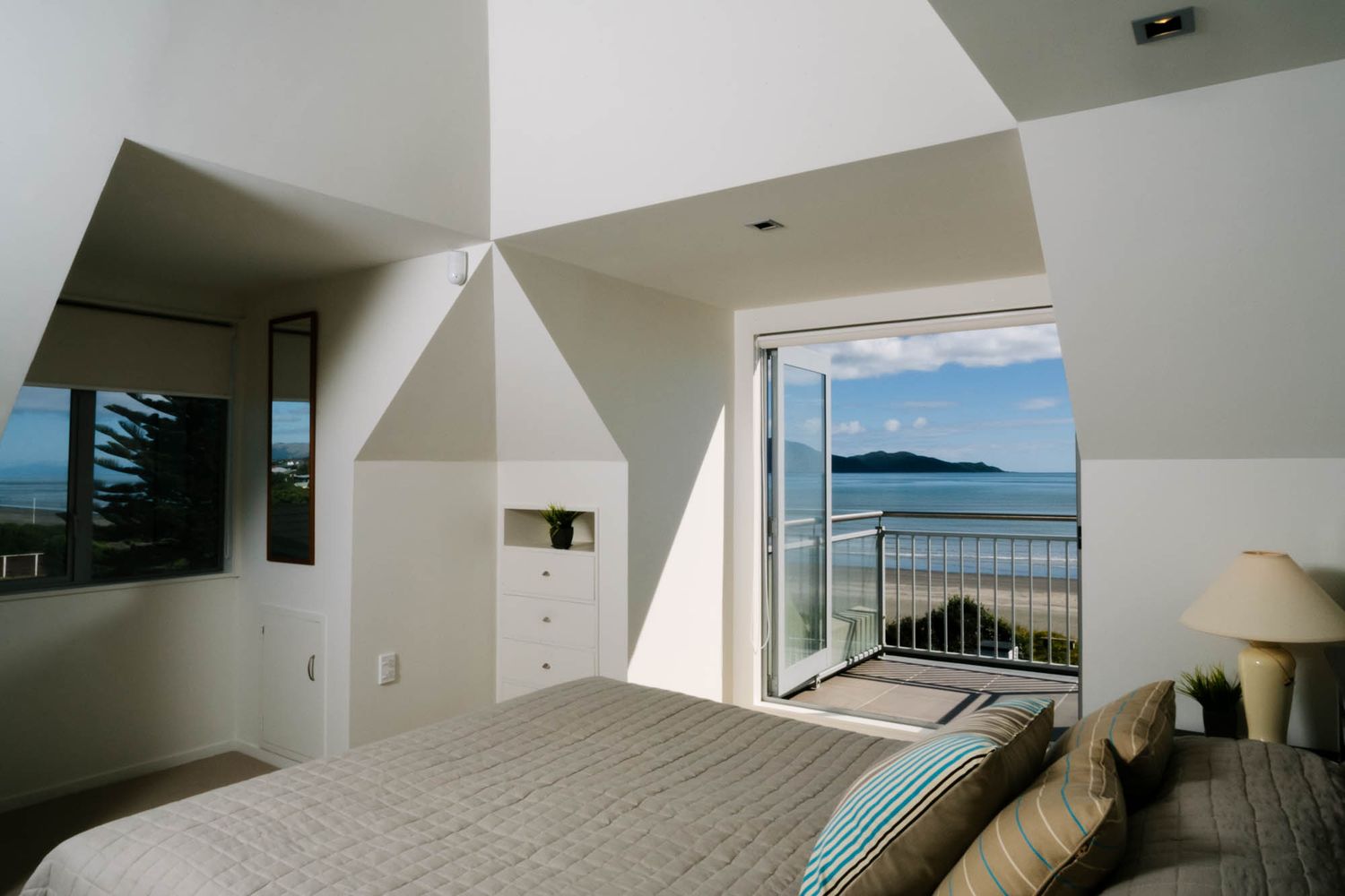Contemporary white interior space with floor-to-ceiling windows offering panoramic ocean views.