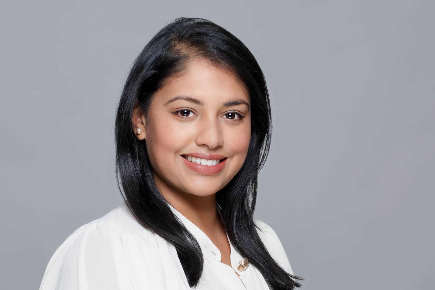 Professional headshot against grey background showing warm expressions.