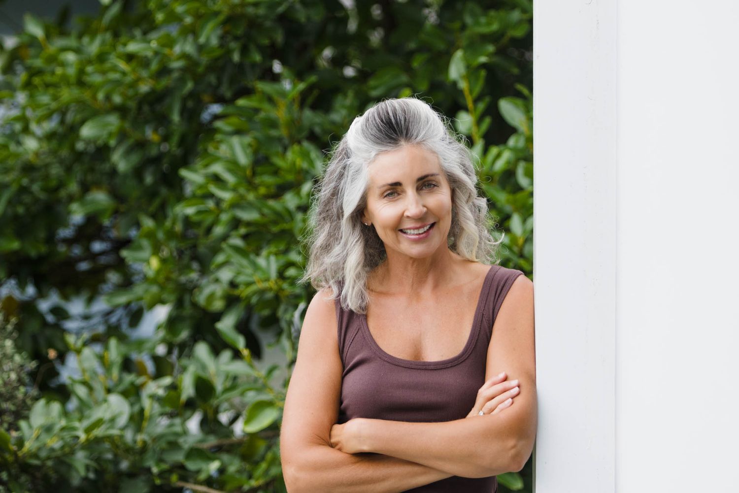 Jo Williment of Sage Studio outdoors against lush green foliage background in casual attire.