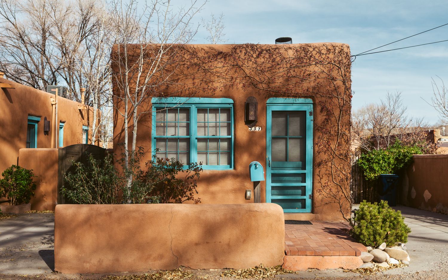 Adobe style buildings with turquoise trim and windows along a street in Santa Fe.