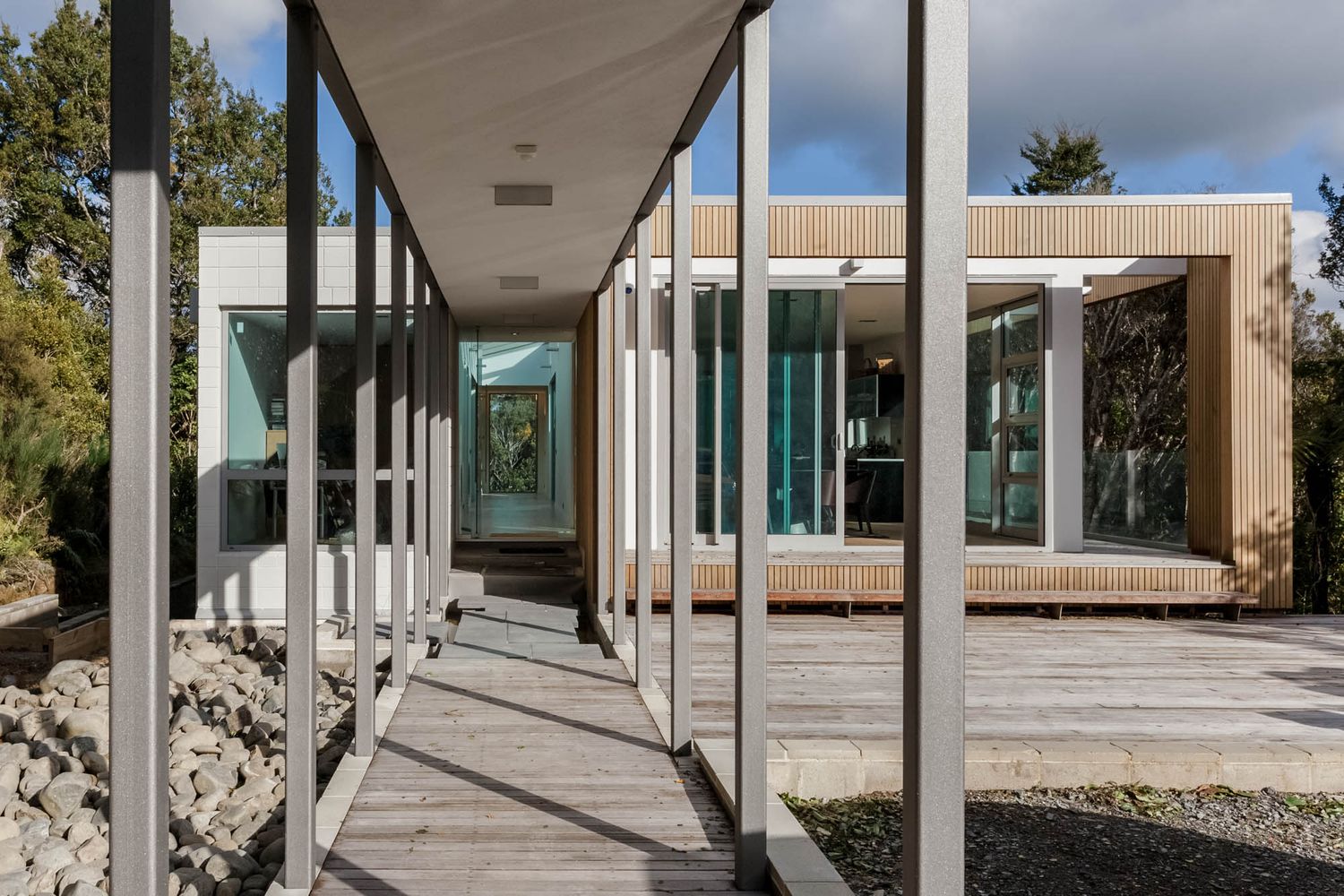 Contemporary covered walkway with concrete pillars and minimalist landscaping.