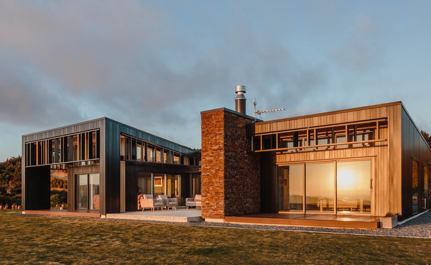 Panoramic sunset view of modern lifestyle house with brick and metal exterior elements.