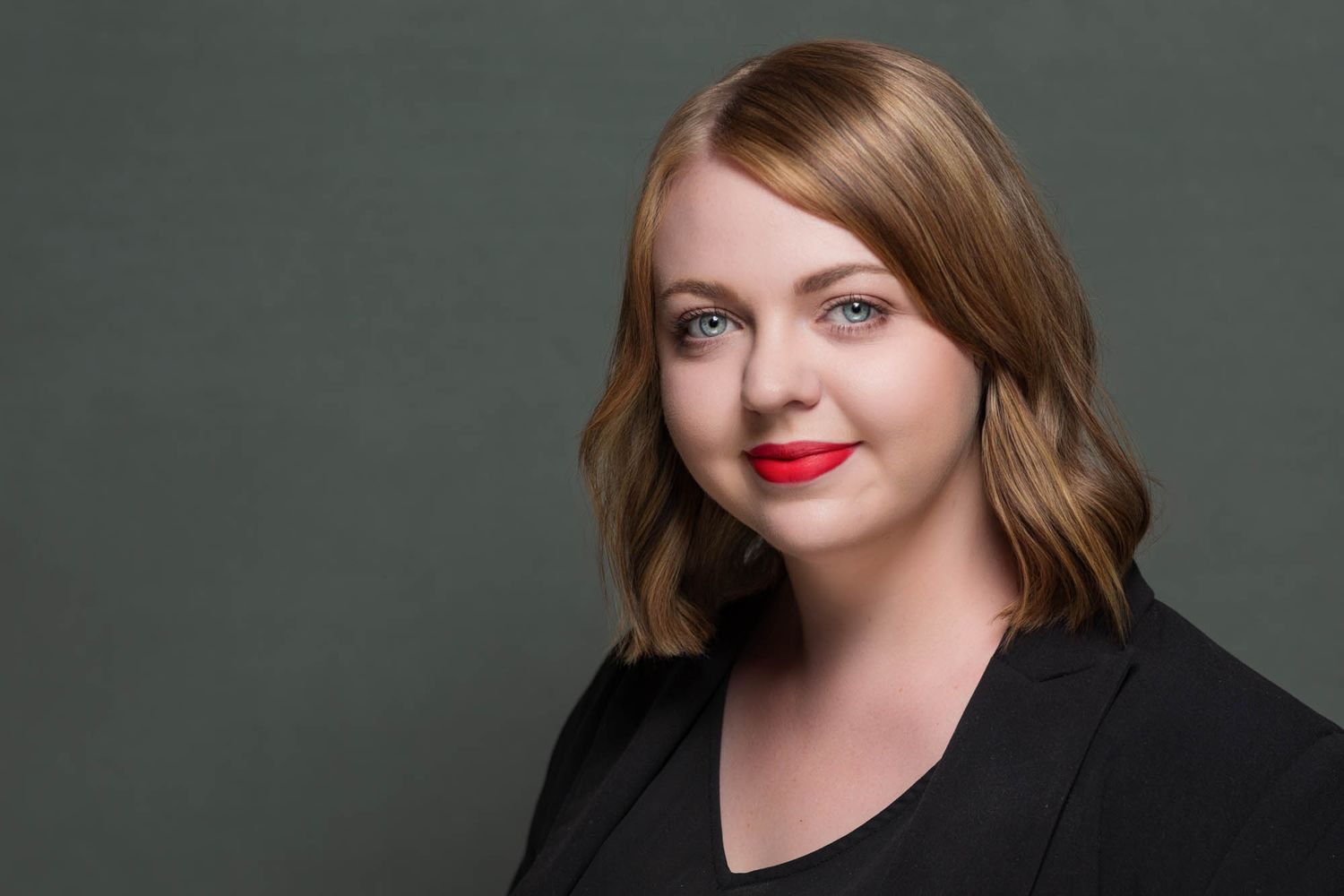 Professional studio portrait against dark grey background with dramatic lighting.