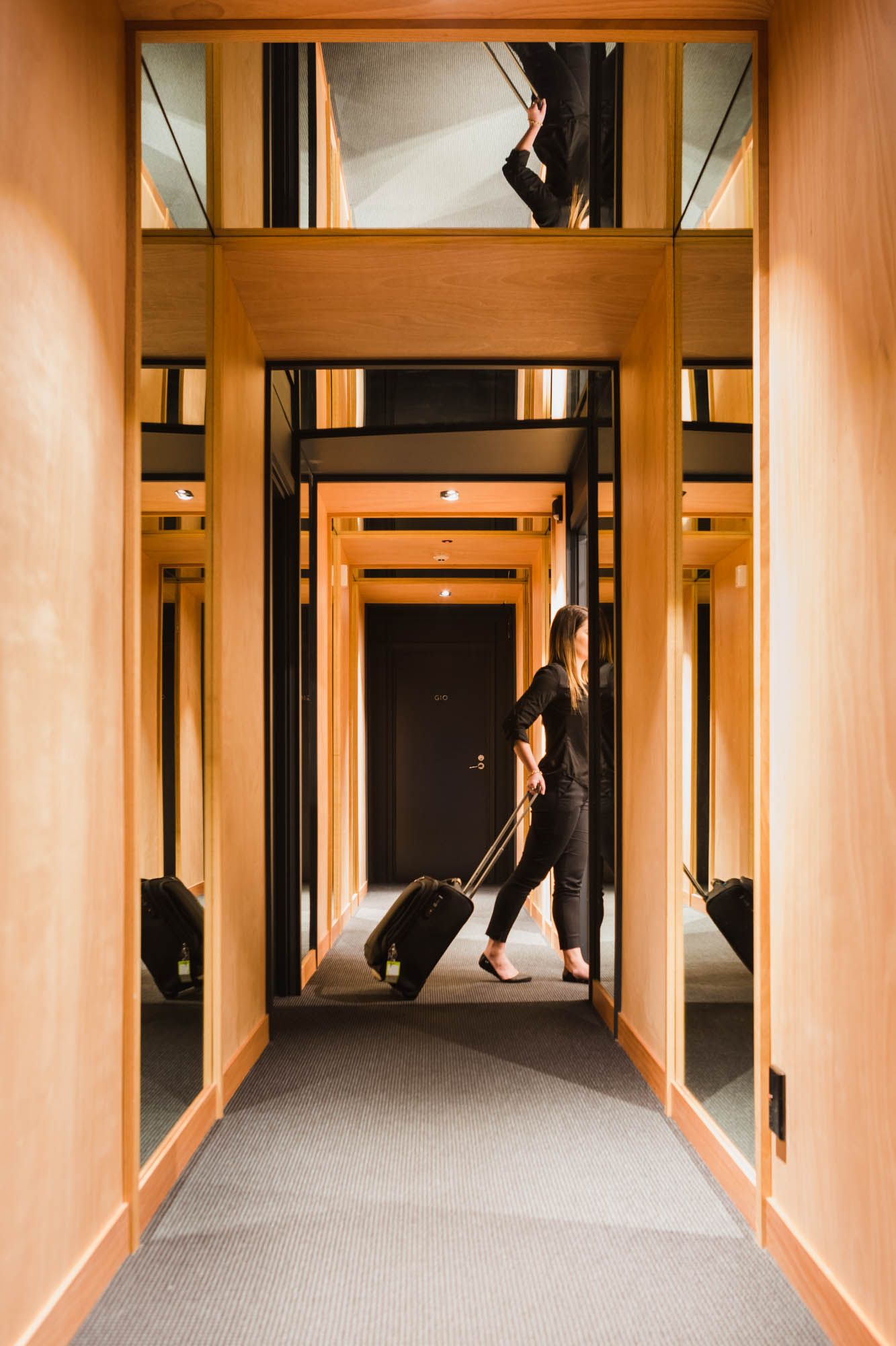 Symmetrical Gilmer Hotel corridor with wood trim and carpeted flooring leading to glass doorways.
