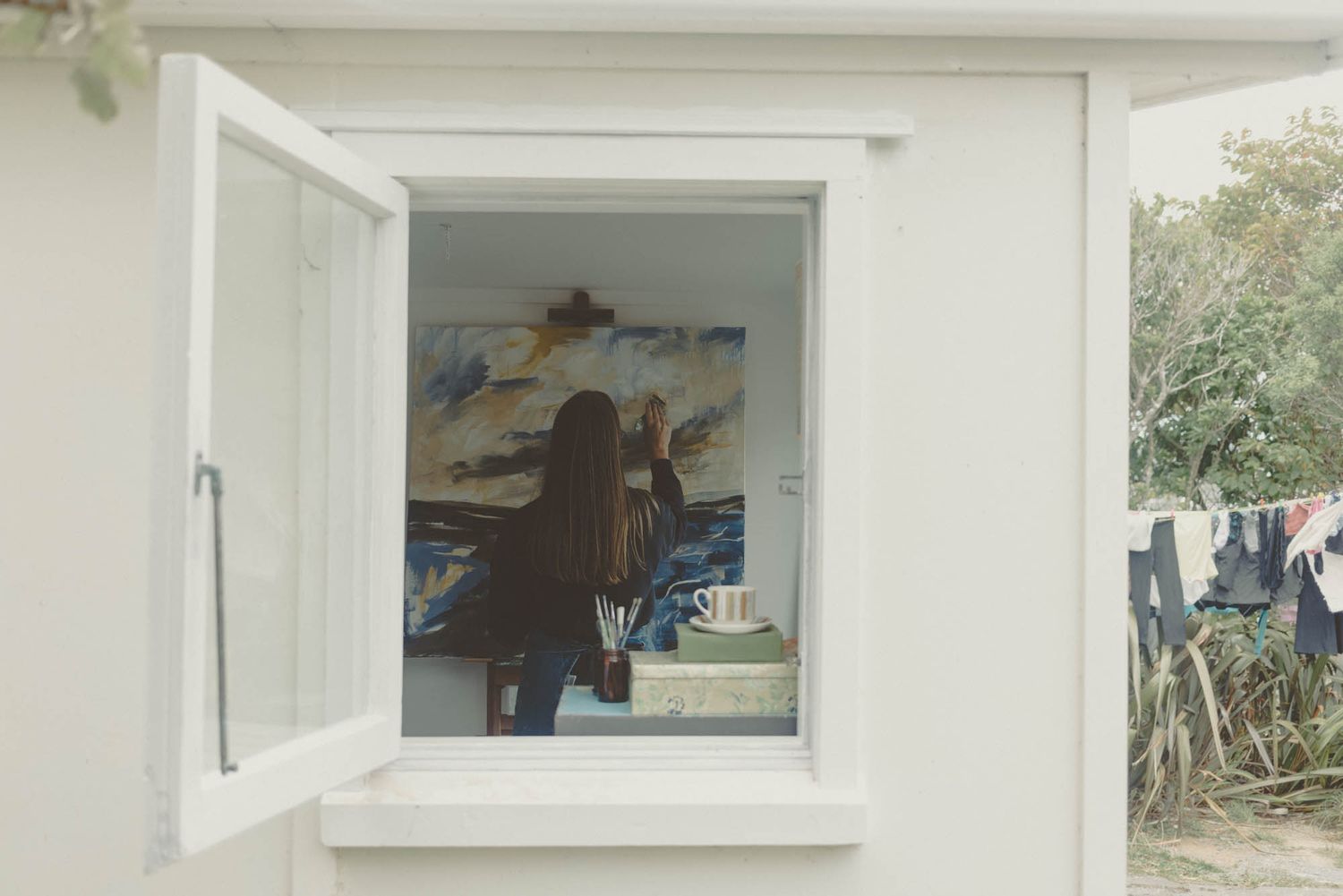 View through a white window frame of an artist's studio space.
