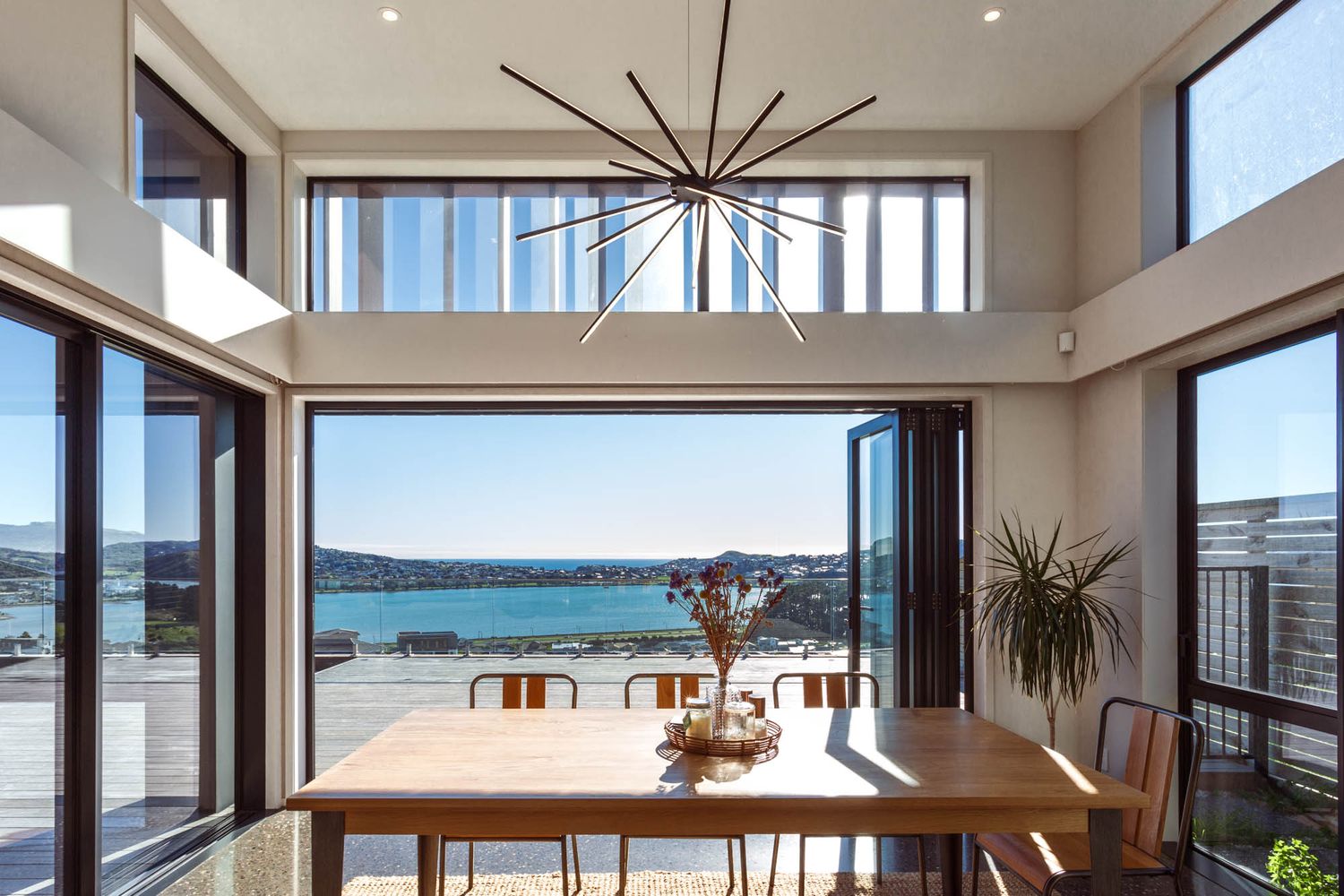 Dining area with large windows offering stunning ocean views and modern pendant lighting.