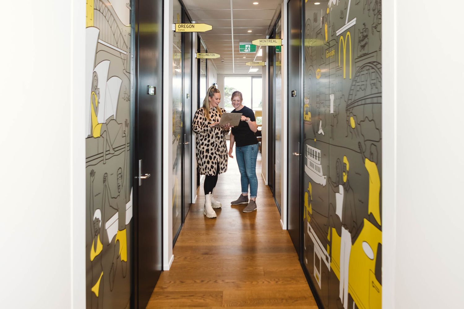 Long office hallway at Arlo with black doors and yellow graphic wall designs.