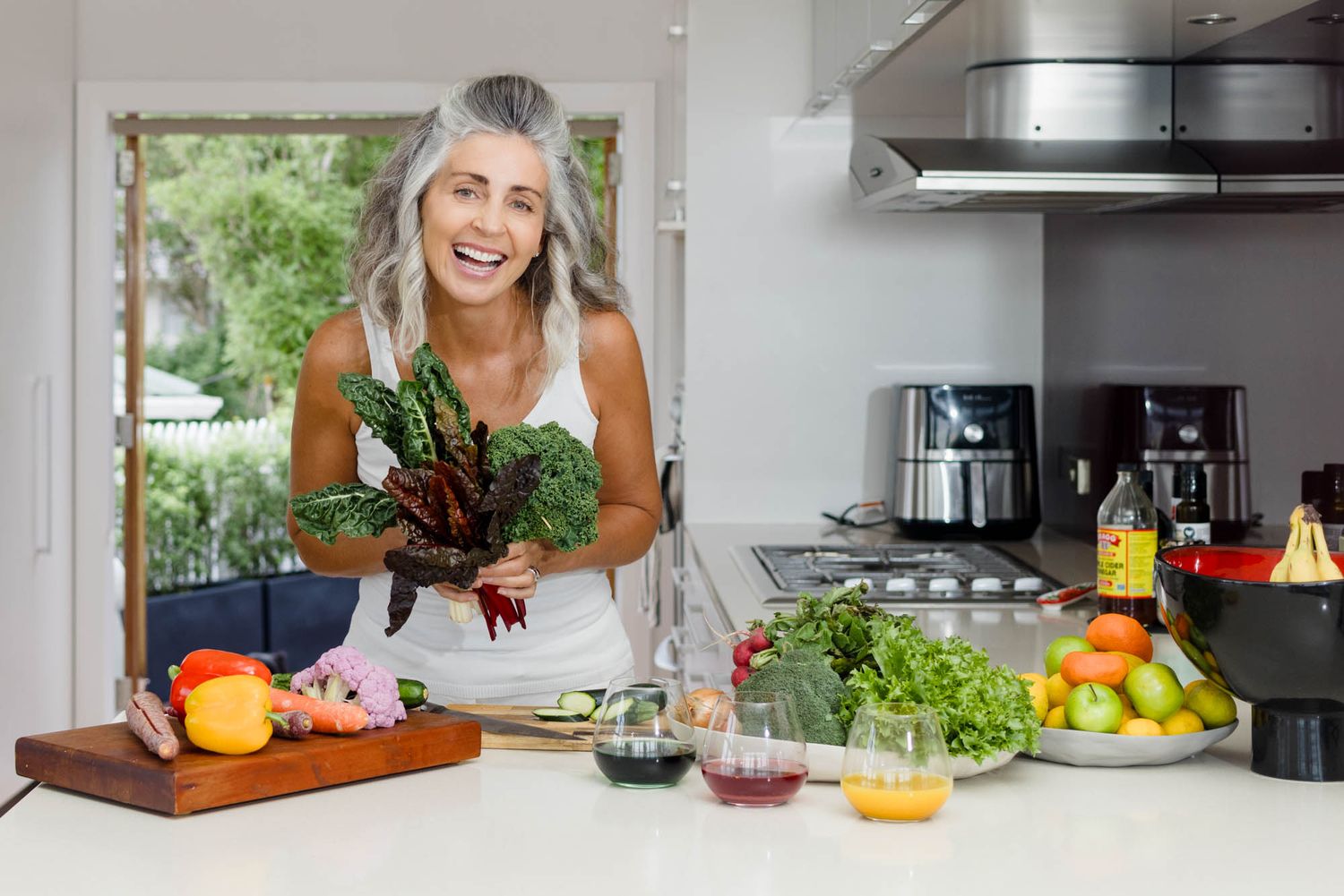 Jo Williment of Sage Studio with fresh fruits and vegetables arranged on a bright modern kitchen counter with natural lighting.