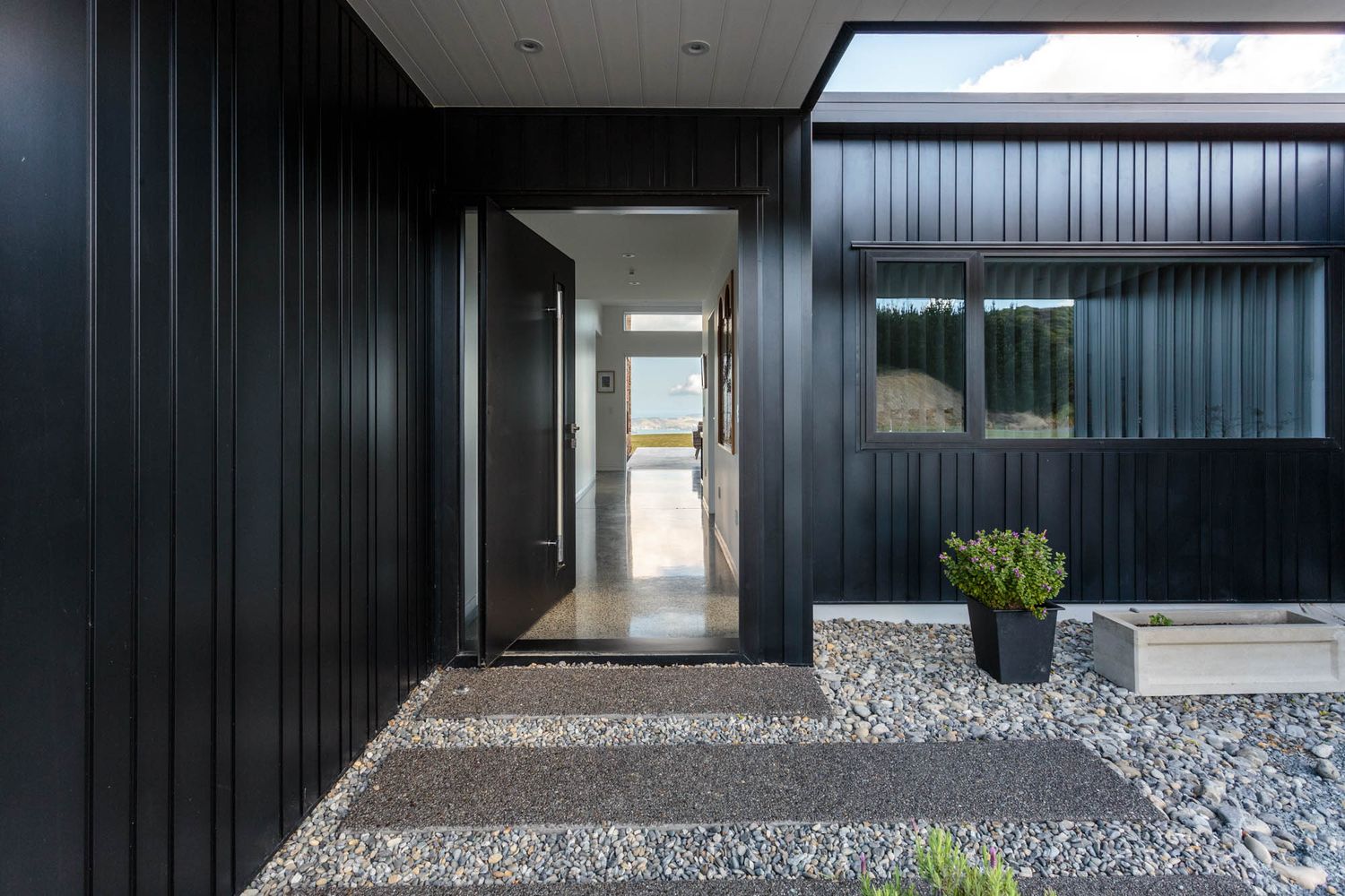 Modern black-clad building exterior with gravel landscaping and minimalist architectural details.