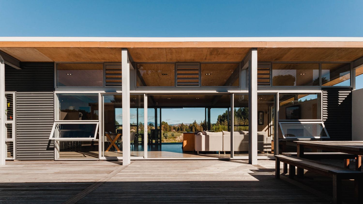 Modern architectural home exterior with clean lines and large windows overlooking a scenic coastal view.