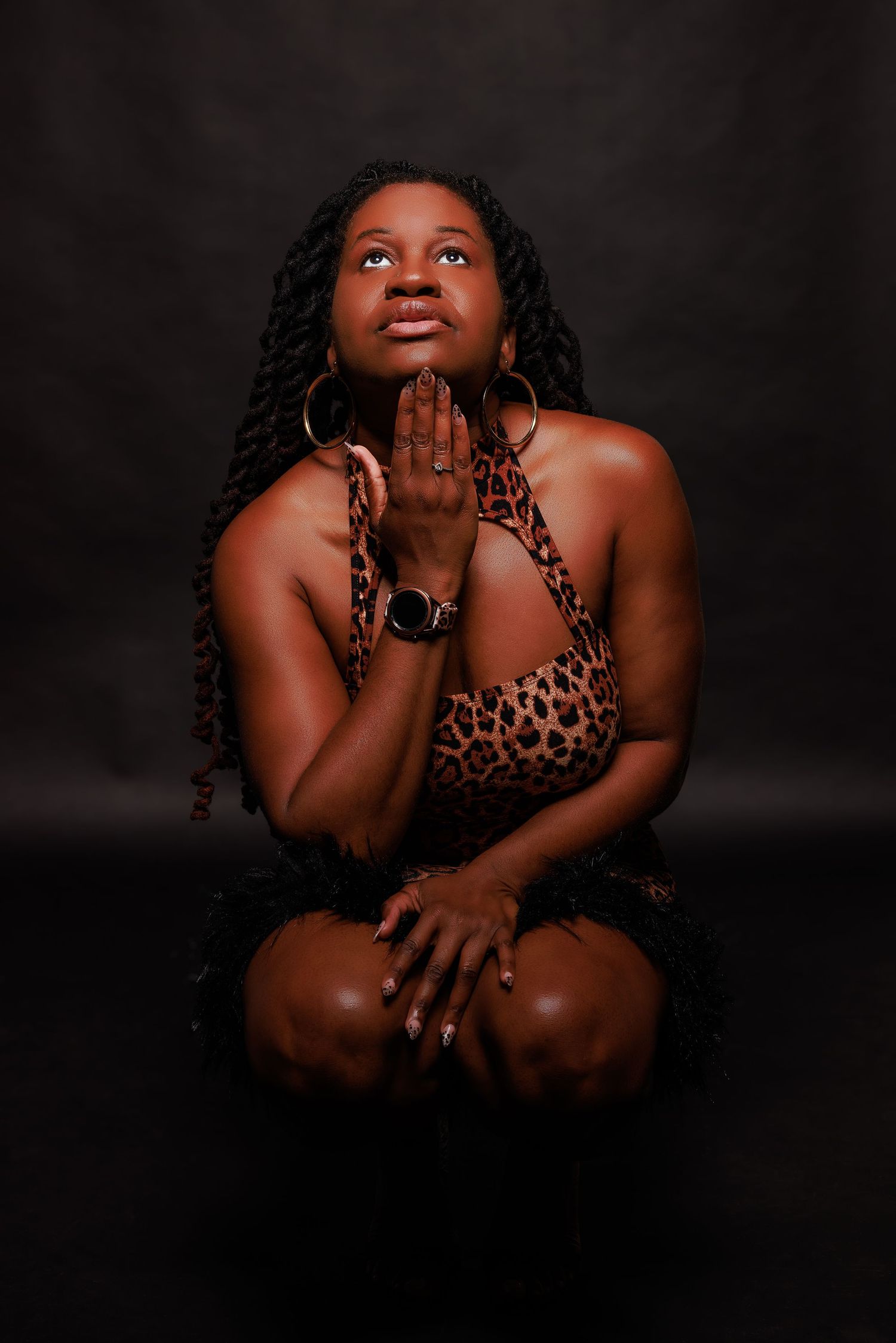 Artistic portrait with person in leopard print top against dark background with dramatic lighting.
