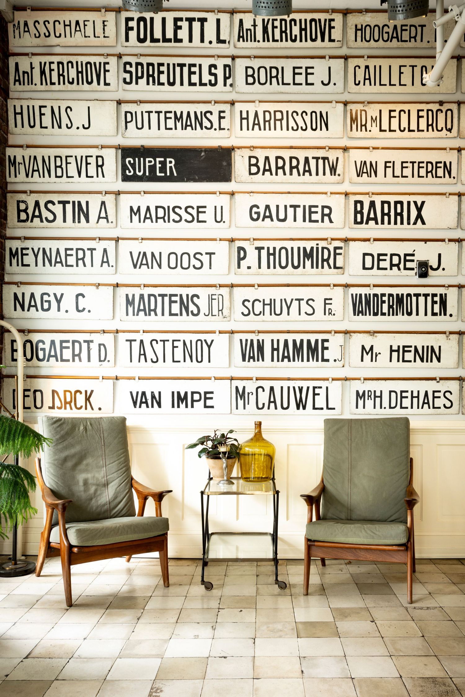 photo of a hotel lobby with two danish modern chairs, plants, and street signs from Denmark adorning the walls