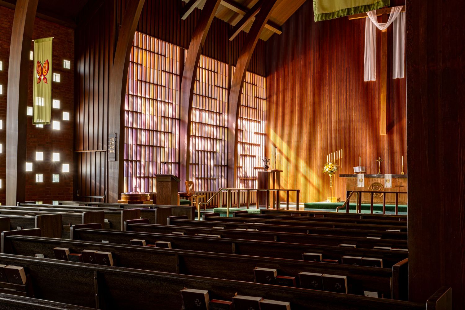 Shot from back of church capturing pews, sun streaming through windows, and altar; Zion Lutheran Church
