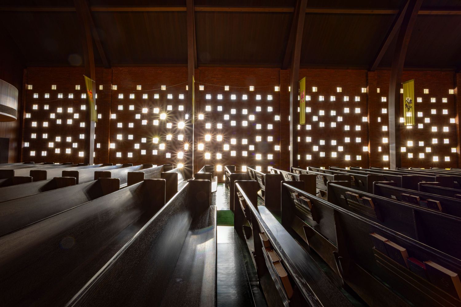 Sun shining through patterned openings in the wall onto pews, Zion Lutheran Church