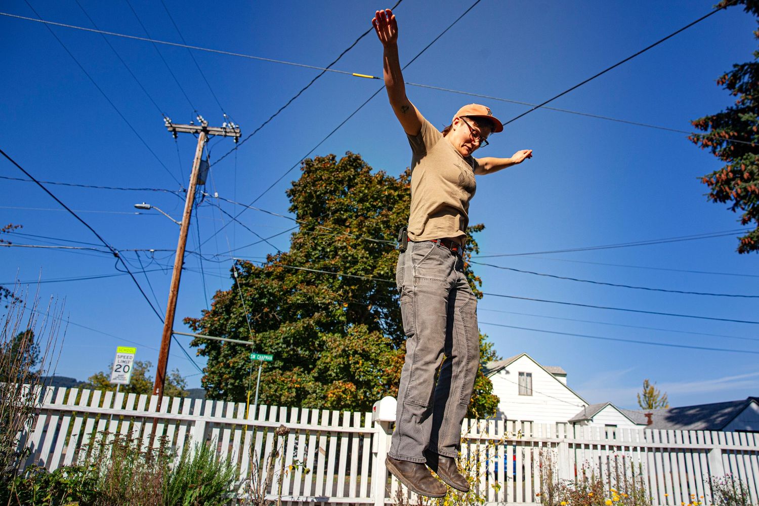 Photo of a woman jumping into the air with arms outstretched against a blue sky