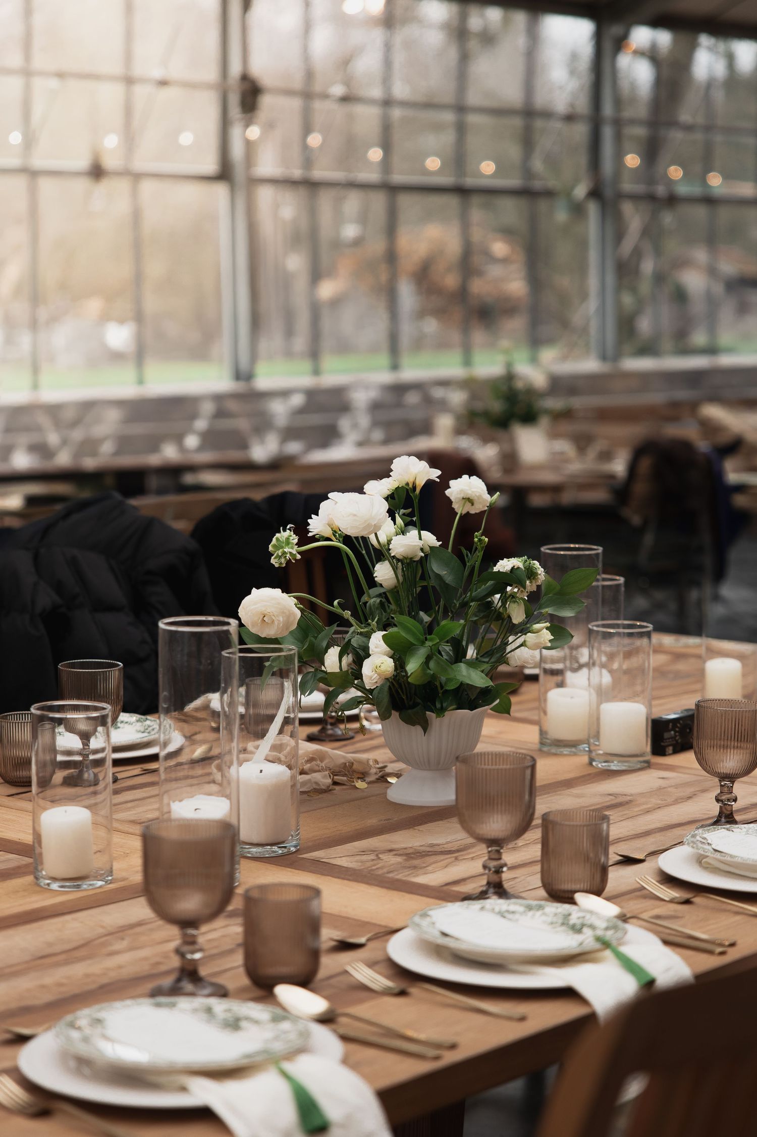 Hochzeit im Glashaus Galanthus by Bisteria: Elegante Tischdeko mit weißen Blumen & Kerzen. Hochzeitslocation München.