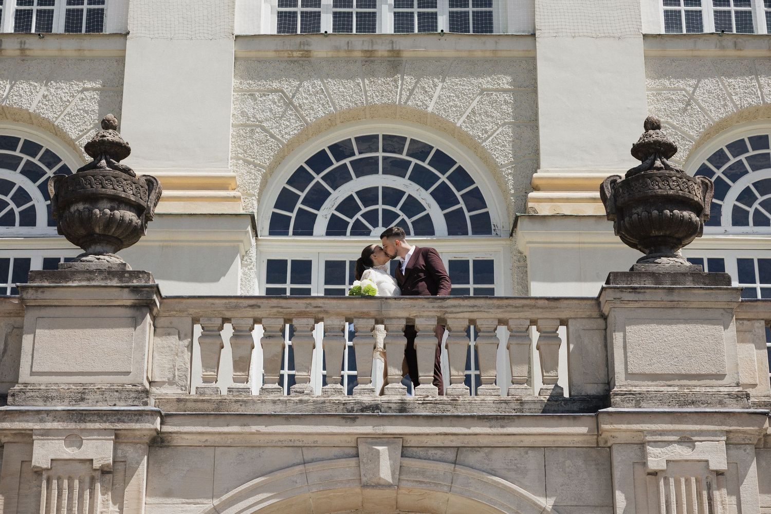 Brautpaar küsst sich auf dem Schlossbalkon: After-Wedding-Shoot am Schloss Nymphenburg. Elegante Standesamt Fotografie in München.