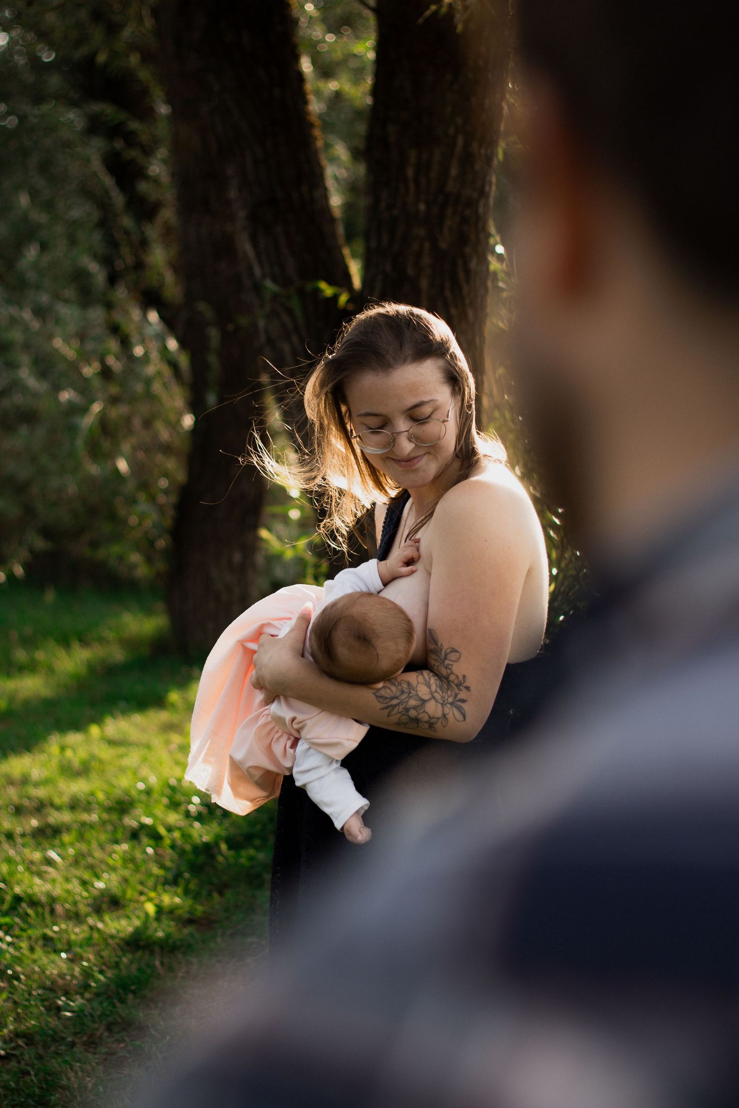 Natürliche Neugeborenenfotografie in Pfarrkirchen: Eine junge Mutter hält ihr Baby behutsam im Arm während eines herbstlichen Outdoorshootin