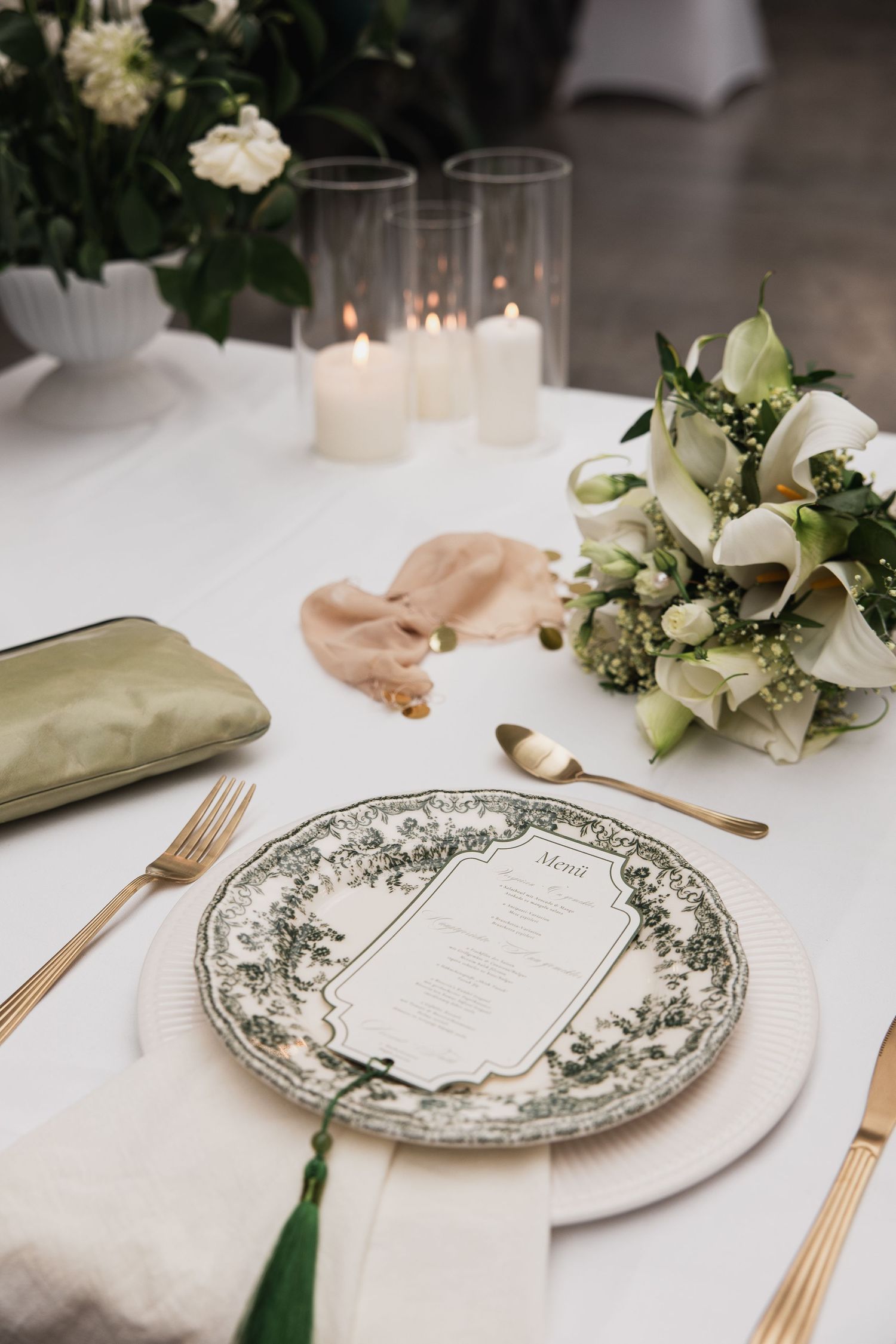 Edle Tischdekoration Calla-Brautstrauß und Menükarte auf festlich gedecktem Tisch in der Glashaus-Location bei München.