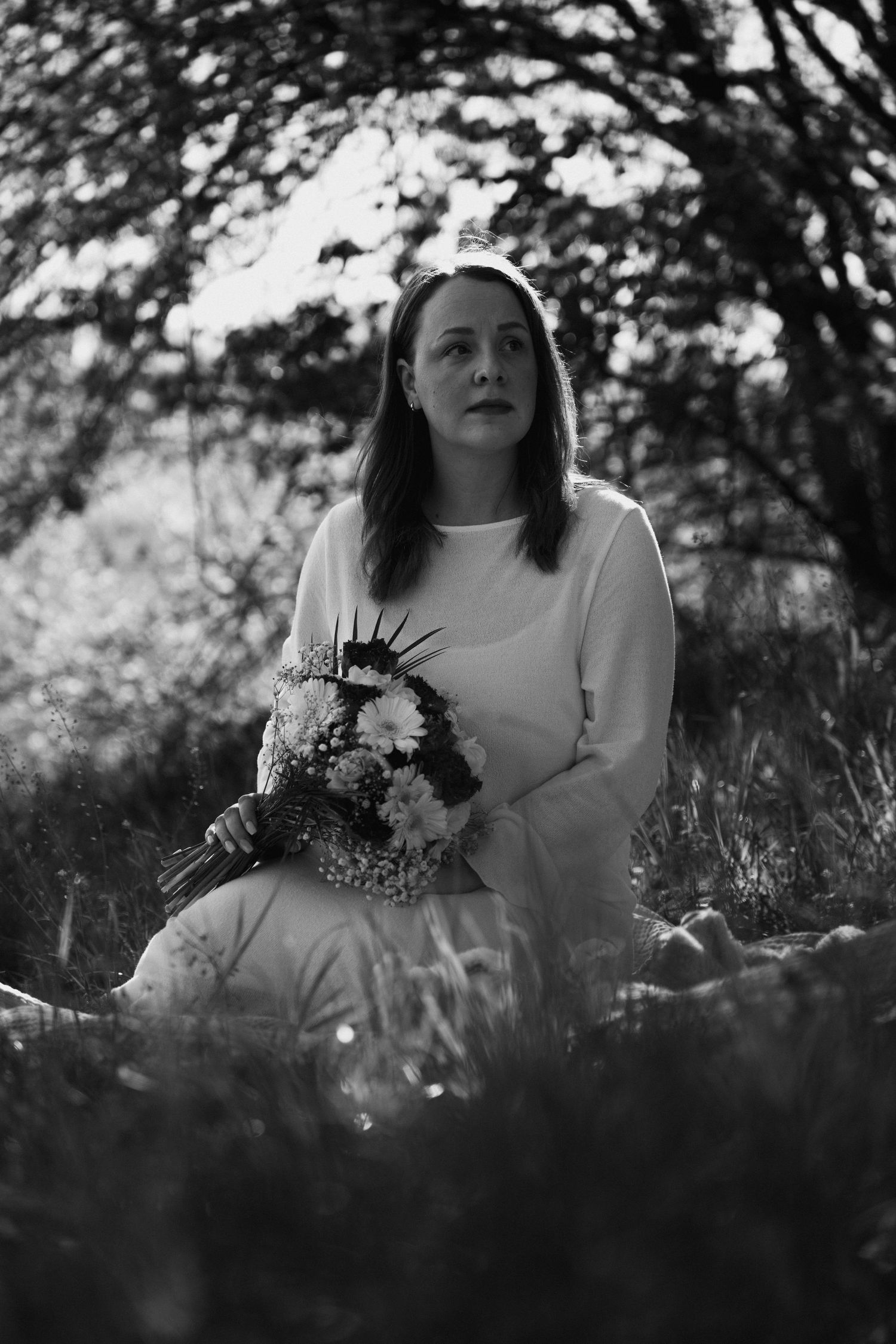 Schwarz-weiß Porträt einer jungen Frau mit Blumenstrauß während eines Lifestyle-Shootings in der Natur.