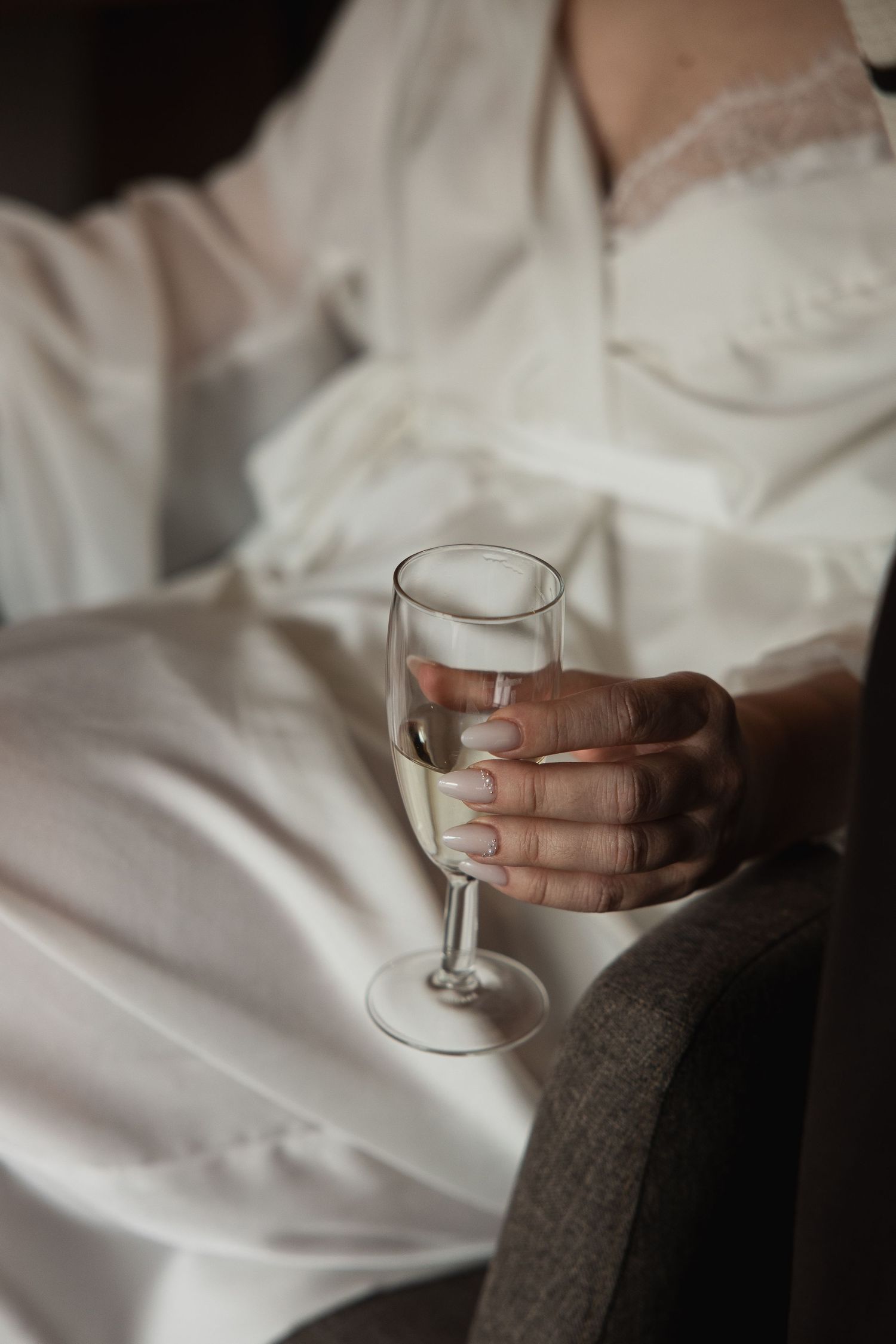 Getting Ready in München: Braut im weißen Morgenmantel mit Champagnerglas. Stilvolle Hochzeitsfotografin Niederbayern.
