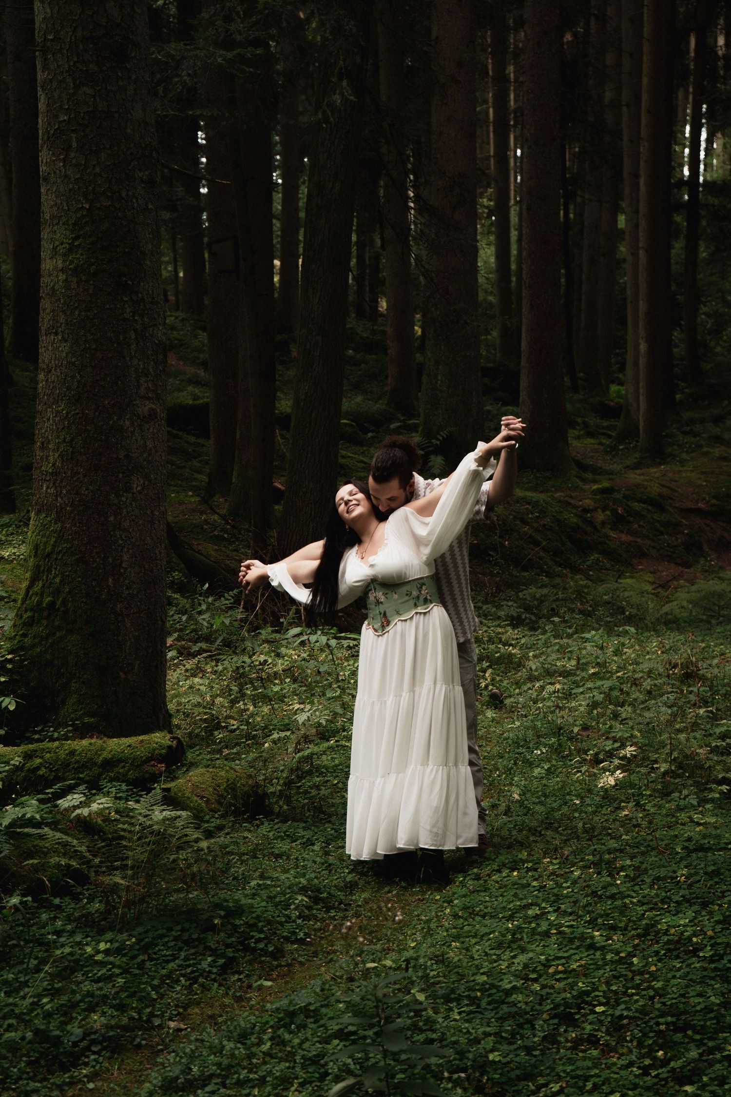 Fine Art Paarshooting im Wald bei Bad Birnbach: Romantischer Kuss zwischen Tannen. Authentische Hochzeitsfotografie Bayern.