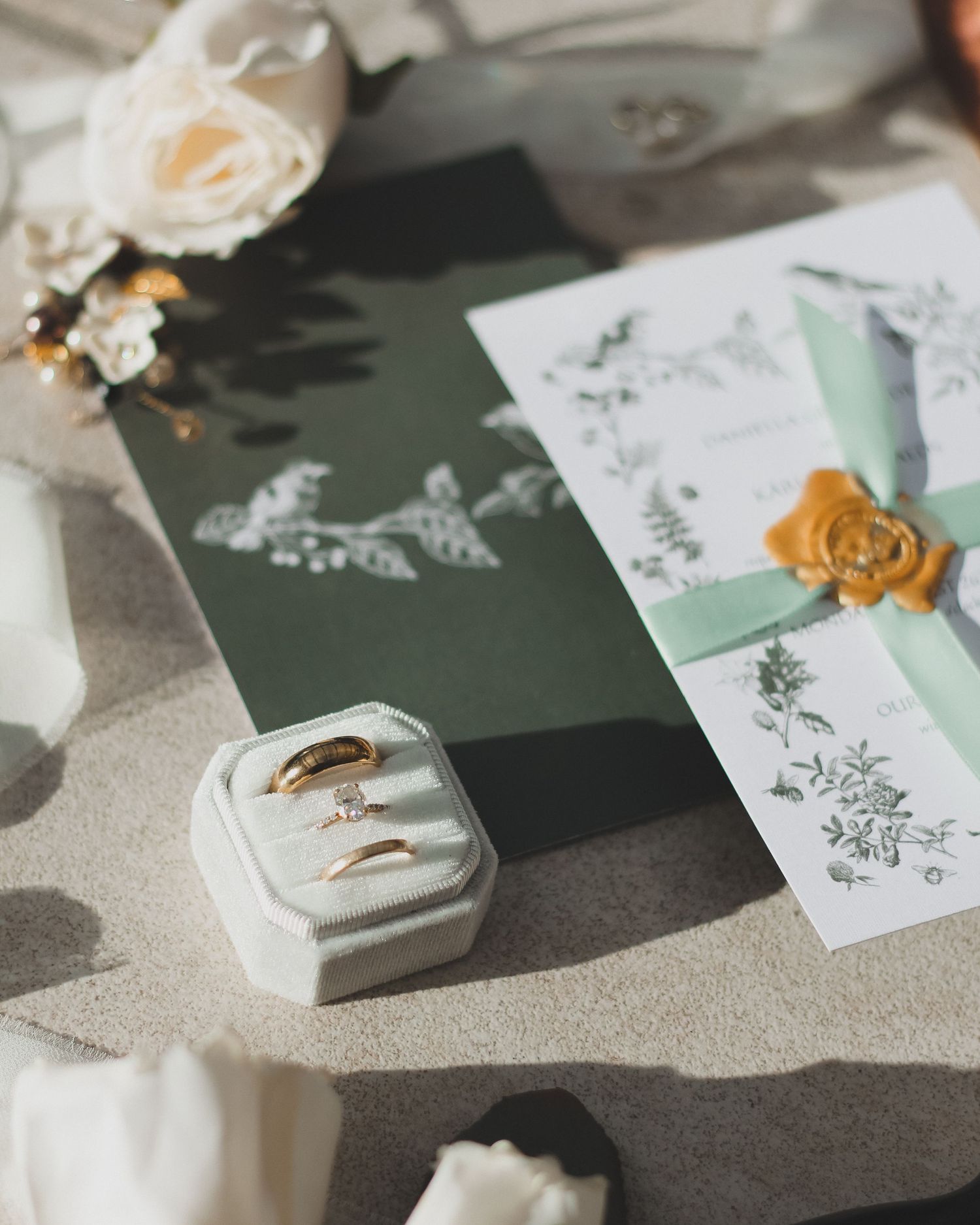 Elegante Hochzeitseinladungen mit Wachssiegel und Eheringen in einer Samtbox.