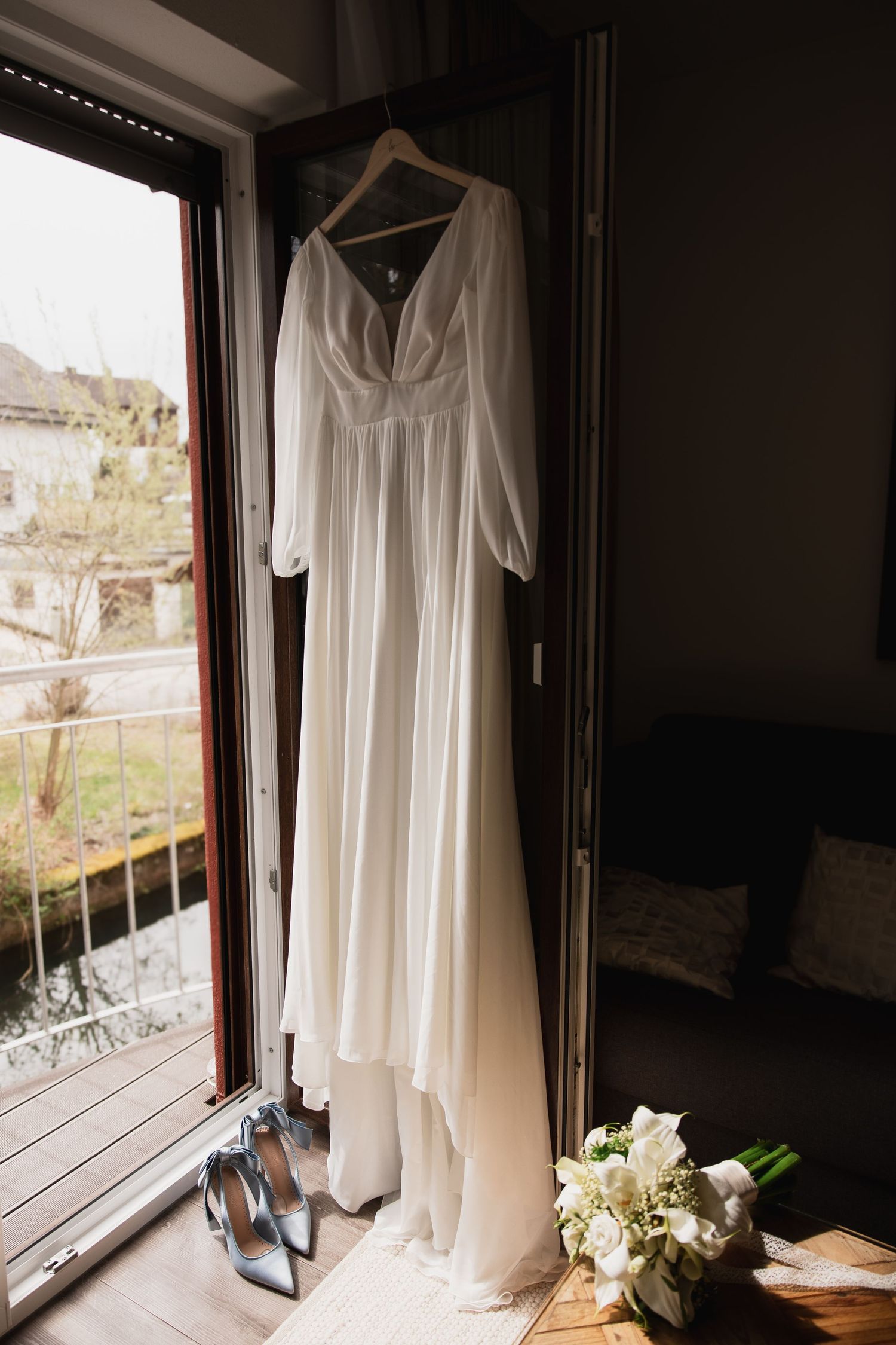 Modernes Brautkleid am Fenster bei Galanthus by Bisteria. Professionelle Hochzeitsfotografie im Glashaus bei München.