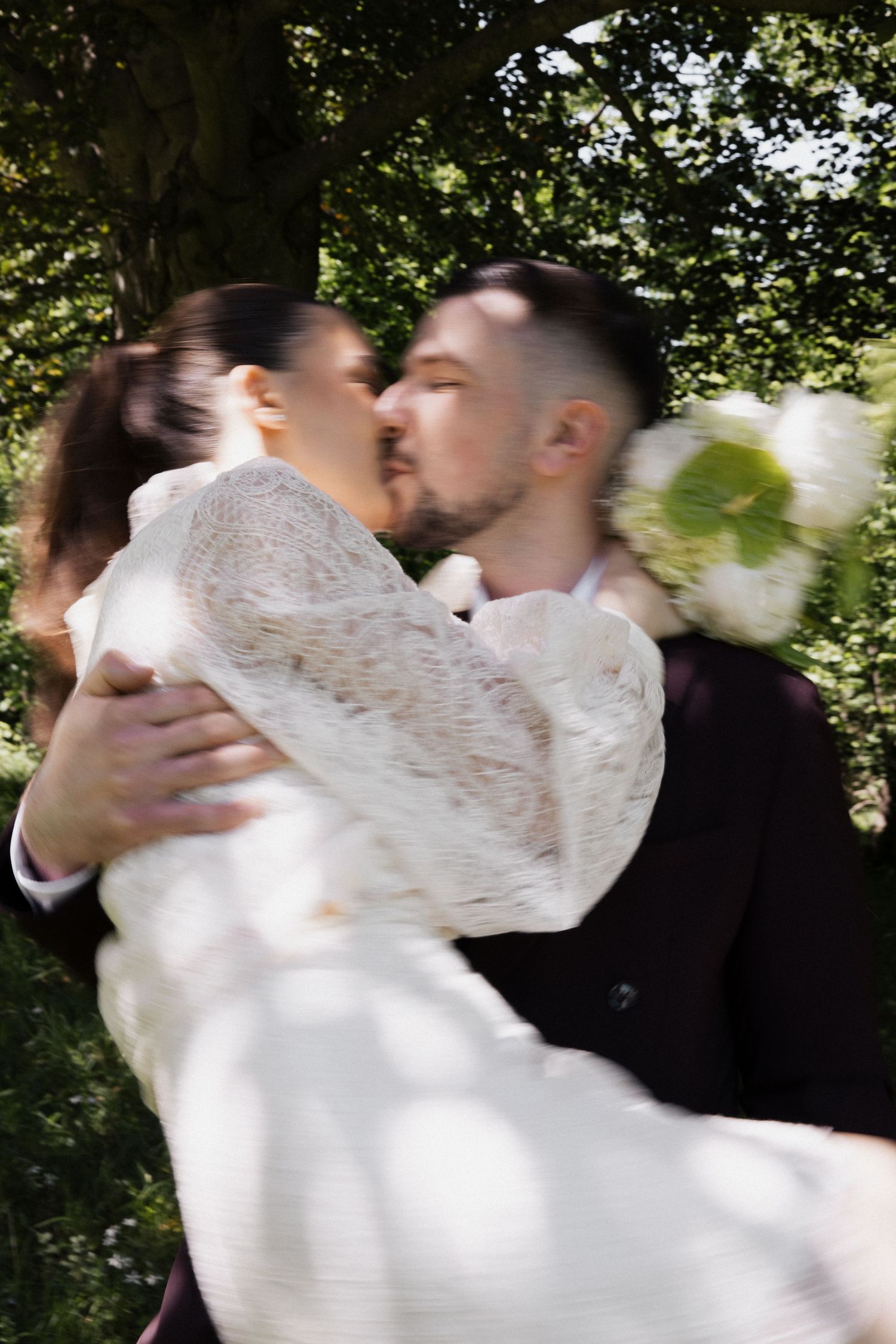 Bewegungsunschärfe beim After-Wedding-Fotoshooting: Bräutigam wirbelt Braut im Schlosspark München herum. Emotionale Hochzeitsfotos.