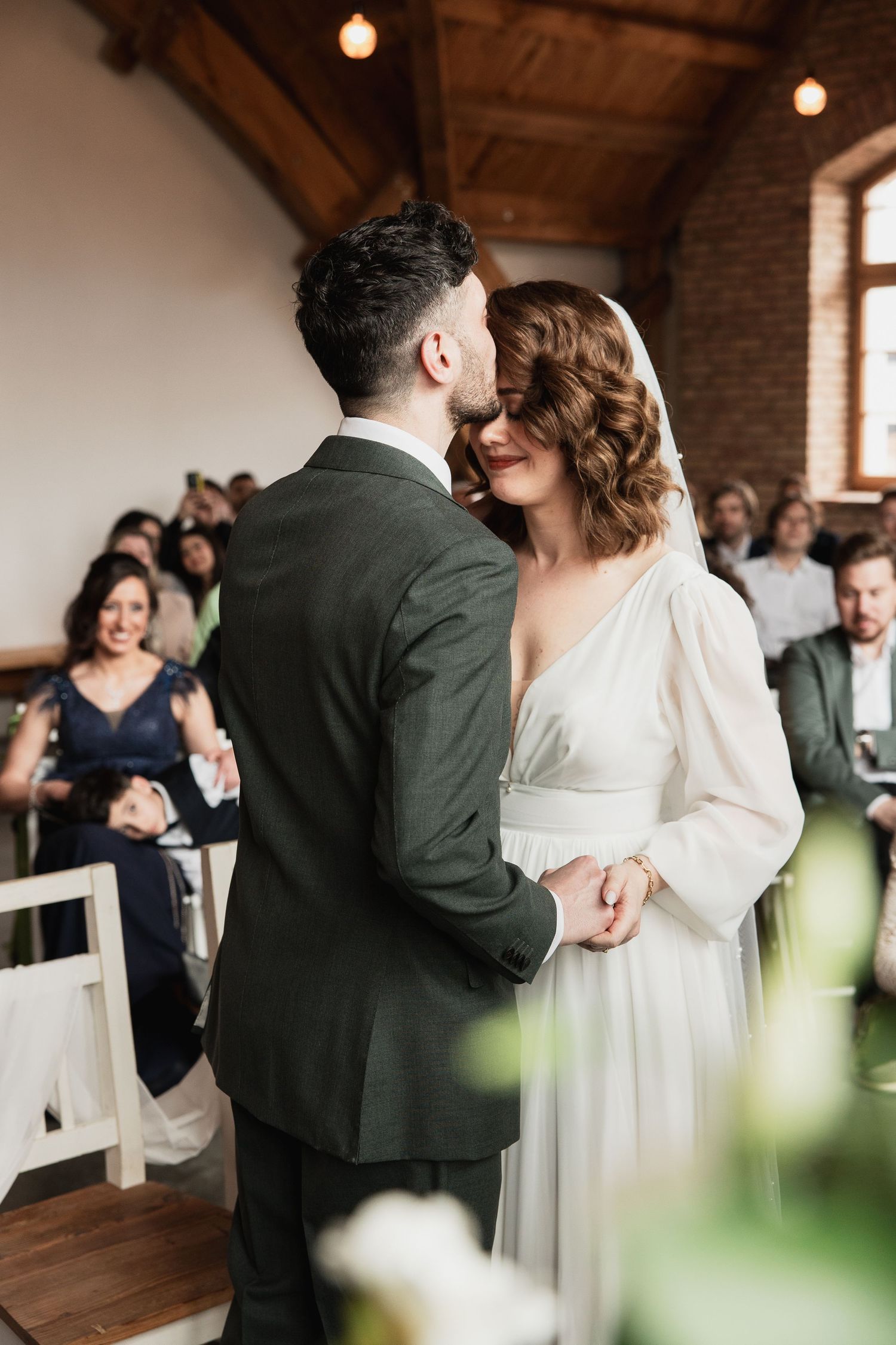 Romantischer Moment bei der Hochzeit in Galanthus by Bisteria: Der Bräutigam küsst die Braut während der Trauung sanft auf die Stirn.