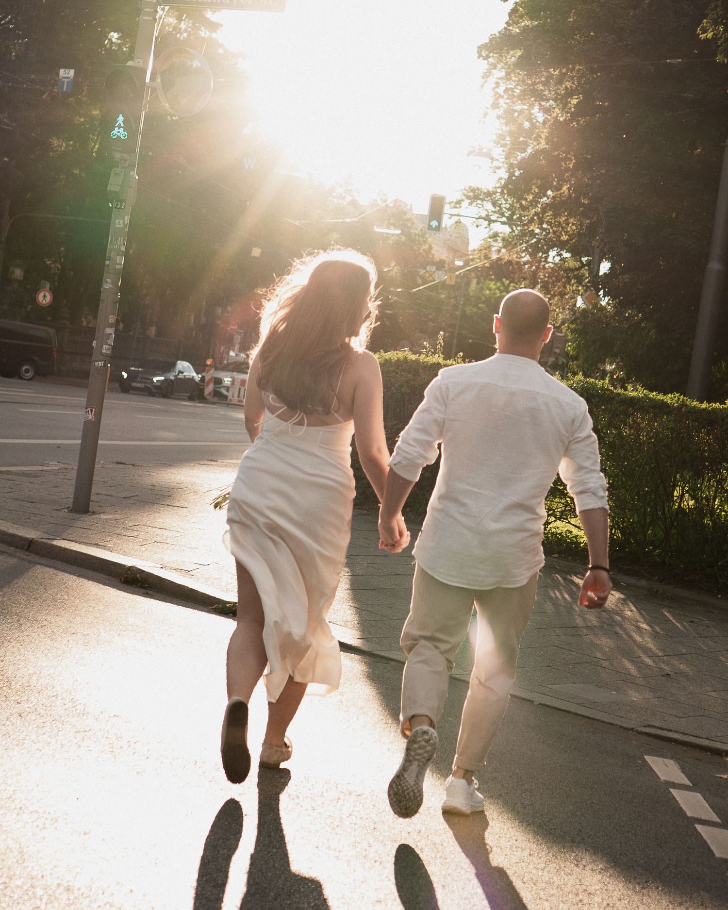 Dynamisches Hochzeitsfoto: Brautpaar läuft Hand in Hand über die Maximilianstraße in München bei Sonnenuntergang.