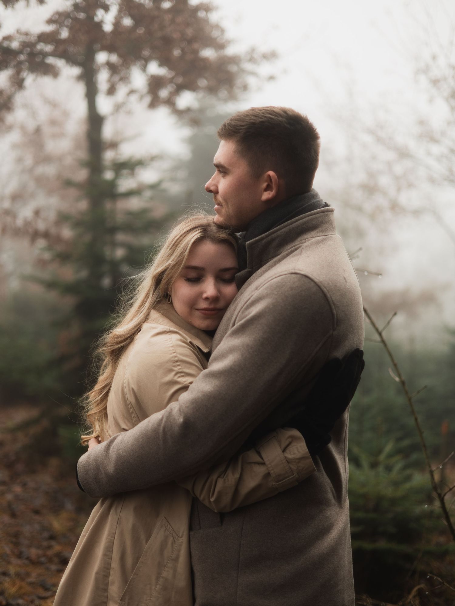 Romantisches Paar-Shooting im Winter: Ein Paar umarmt sich innig auf einer nebligen Weihnachtsbaumkultur in Bad Birnbach.