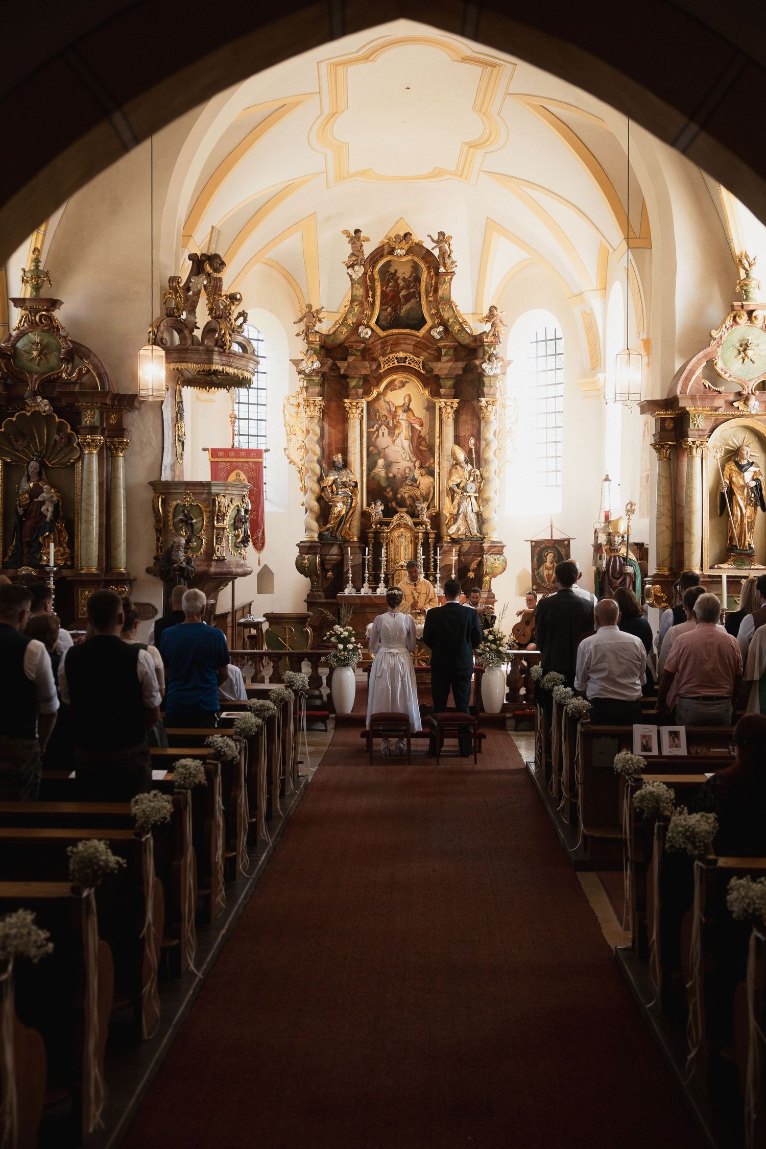 Kirchliche Trauung in Bad Griesbach: Weitwinkel-Ansicht der barocken Kirche während der Trachten-Hochzeit mit Blick zum Altar.