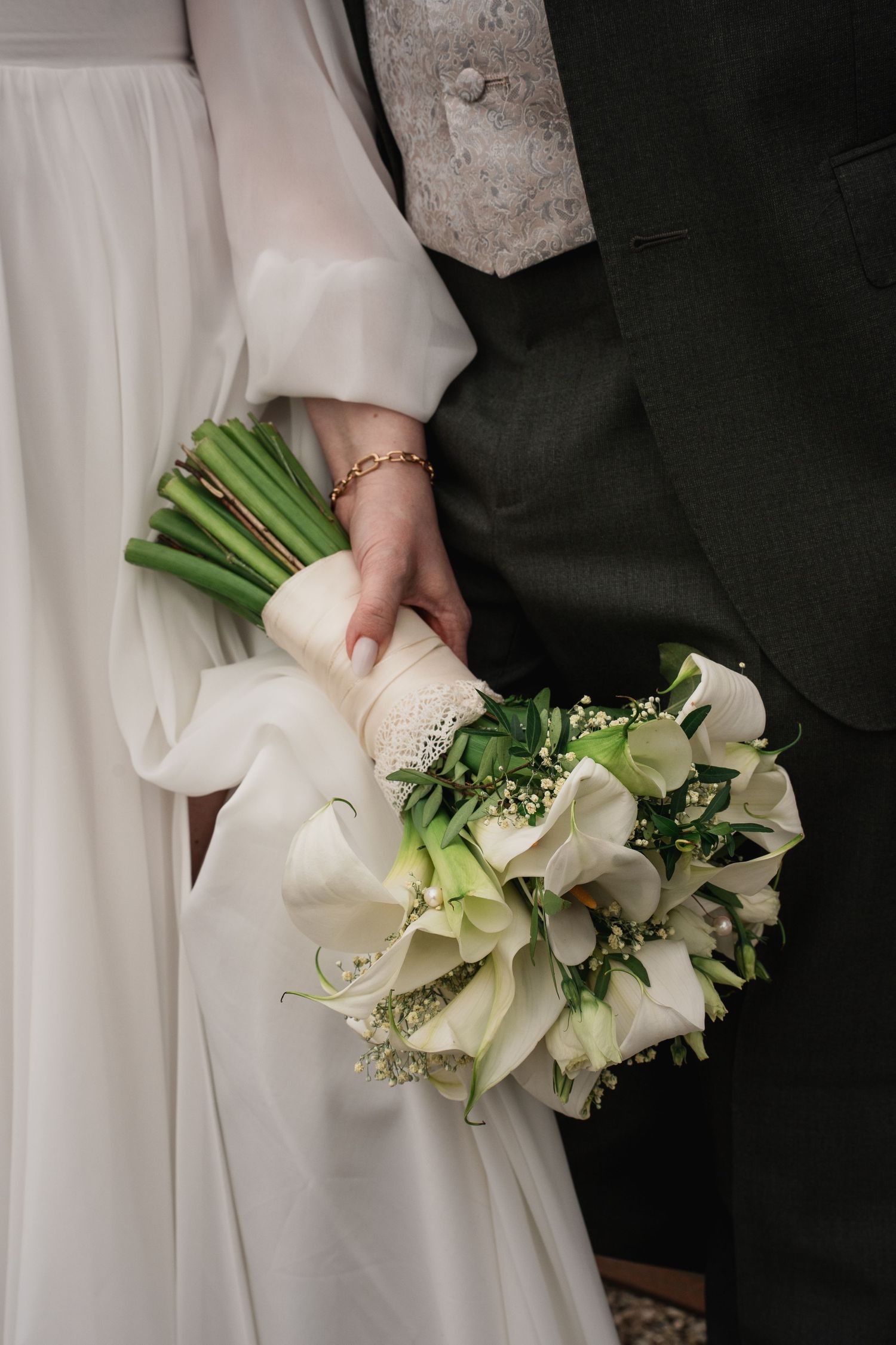 Fine Art Hochzeitsfotografie: Der Bräutigam und die Braut stehen dicht nebeneinander, die Braut hält einen Calla-Strauß