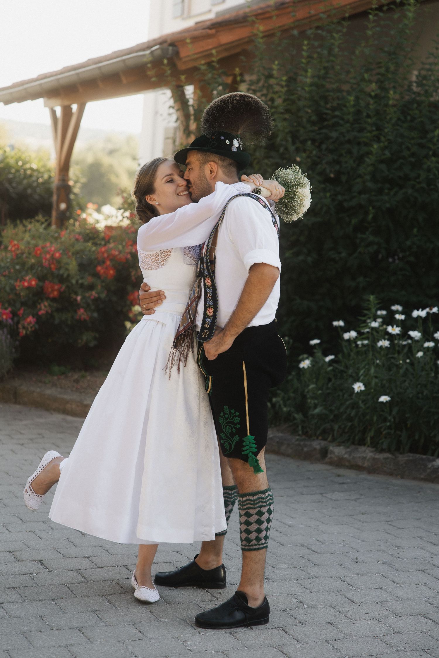 Trachten-Hochzeit im Arterhof Bad Birnbach: Brautpaar in Dirndl und Lederhosen küsst sich glücklich im Freien