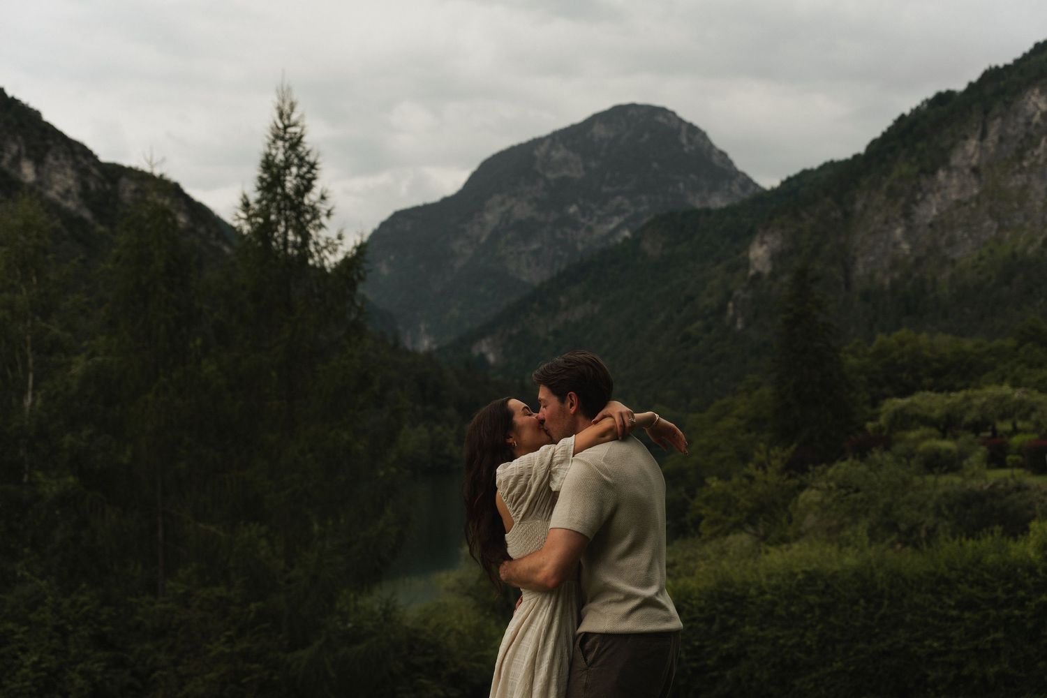 Eine cinematische Aufnahme eines Paares, das sich vor der Kulisse des Thumsees und der Alpen küsst.