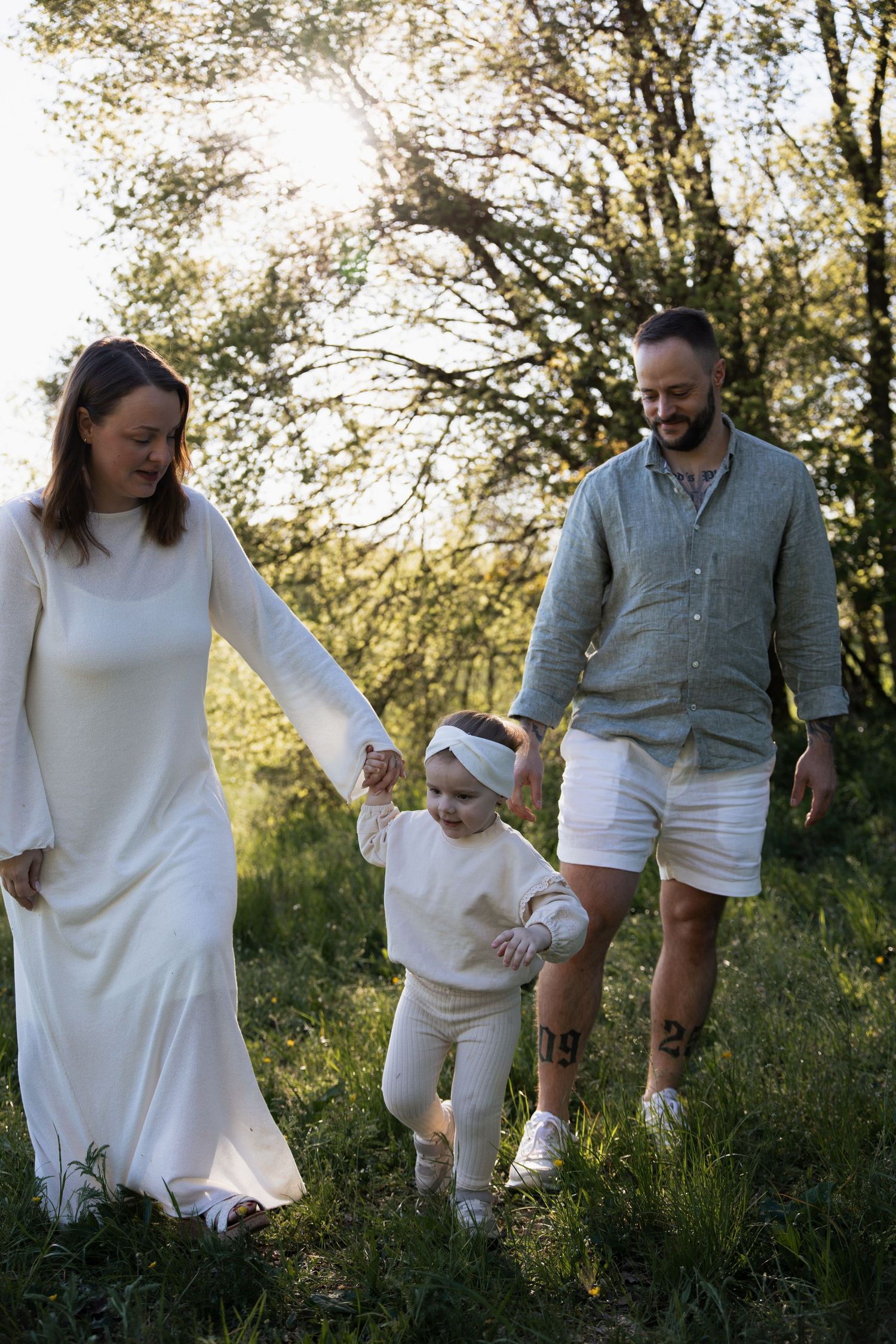 Natürliches Outdoorshooting in Braunau: Eine junge Familie spaziert Hand in Hand bei Sonnenuntergang durch die idyllische Natur Oberösterrei