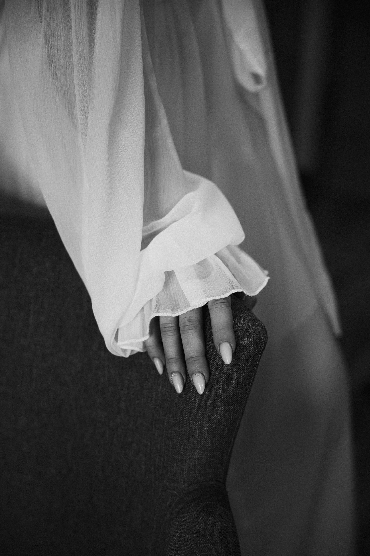Schwarz-Weiß Detail: Filigraner Ärmel des Brautkleids. Fine Art Hochzeitsfotografie für Ästheten in Bayern.