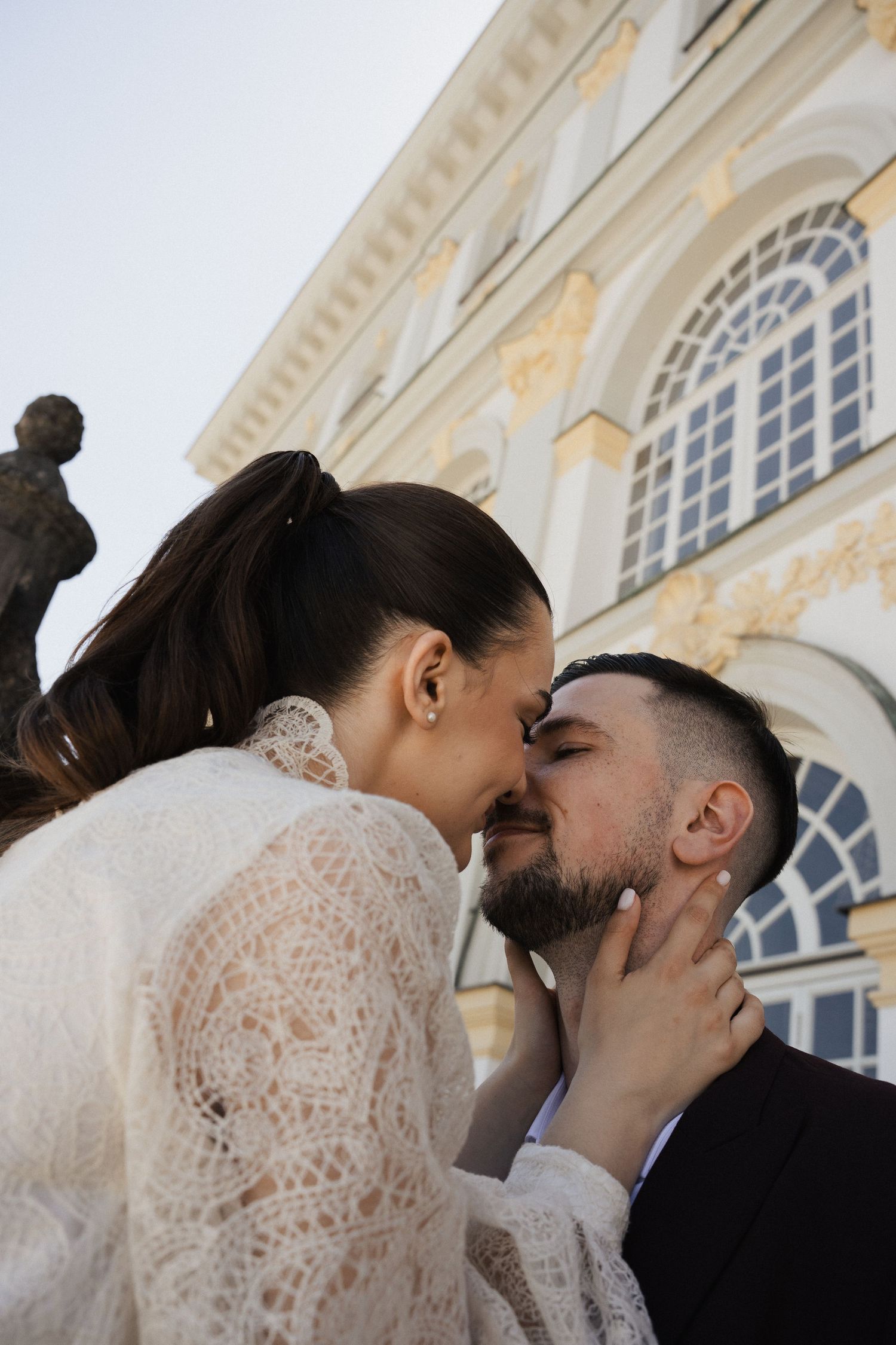 Kreative Perspektive beim After-Wedding-Shoot: Intimer Moment des Brautpaars vor barocker Fassade am Schloss Nymphenburg in München.