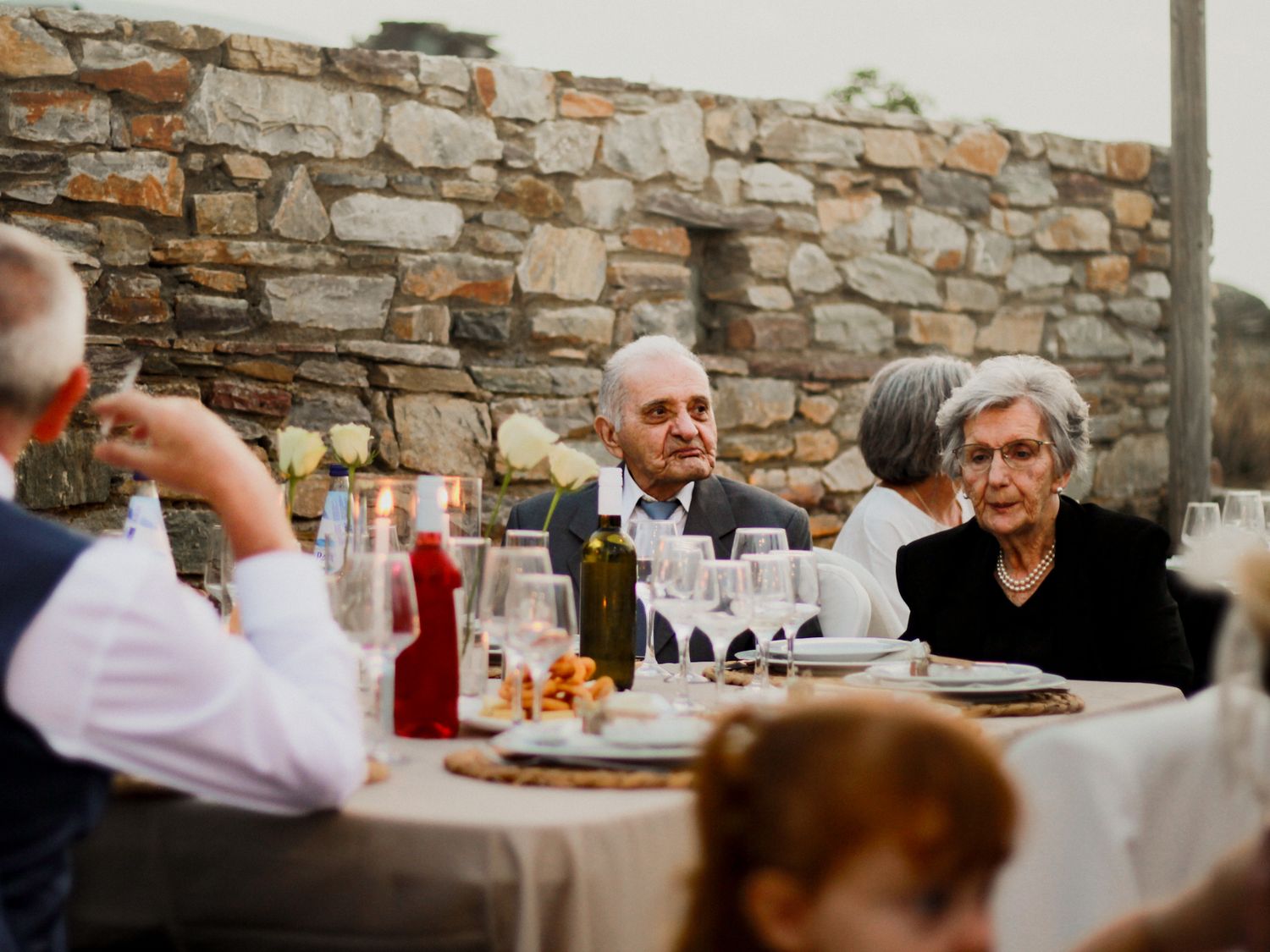 Festliches Abendessen im Freien: Hochzeitsgäste genießen die Feier vor einer rustikalen Steinmauer im Marmari Paradise Resort Hotel in Griec