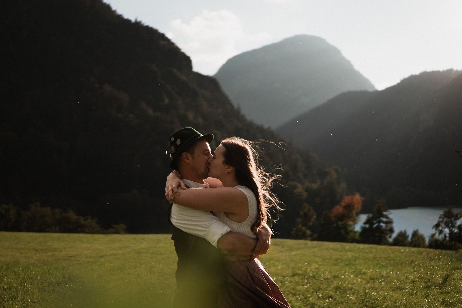 Verlobung in Berchtesgaden: Paar in Tracht auf Almwiese. Authentische bayerische Alpen-Hochzeitsfotos von Ella Grinvalde.