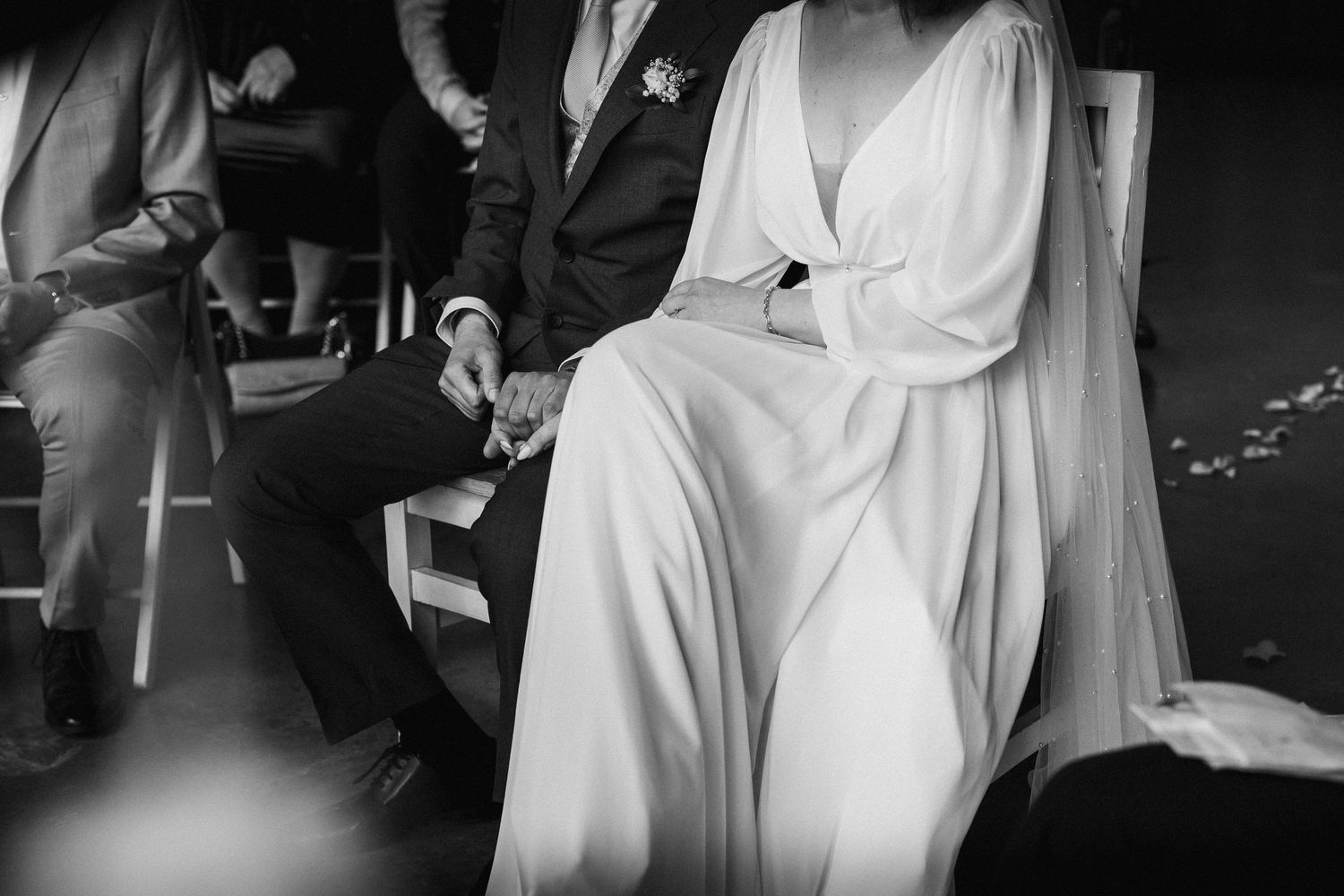 Schwarz-Weiß-Fotografie einer Hochzeit bei München: Das Brautpaar sitzt während der Zeremonie in Galanthus by Bisteria.
