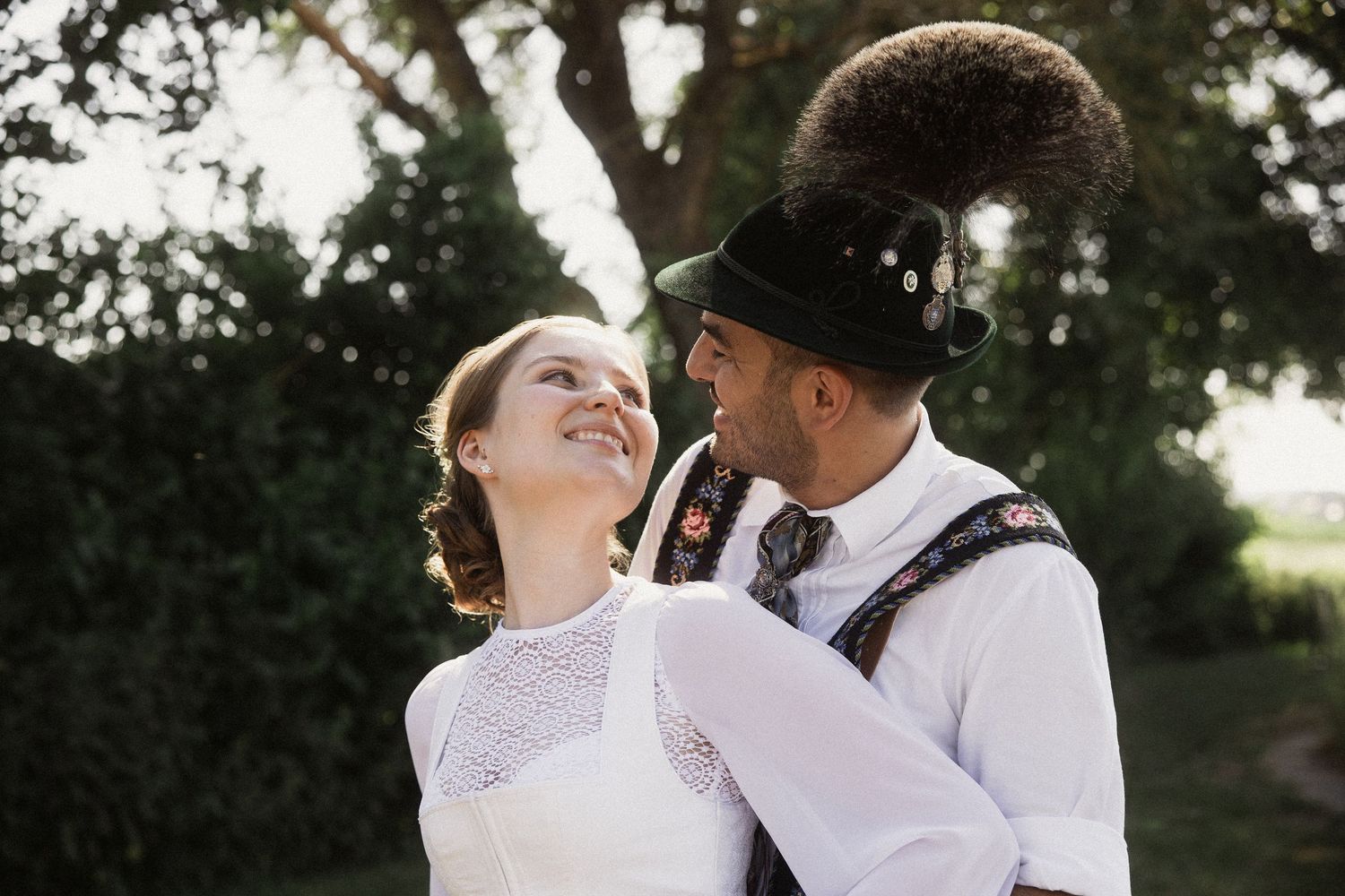 Trachten-Hochzeit im Arterhof Bad Birnbach: Paar in Dirndl und Lederhosen blickt sich beim Porträtshooting verliebt in die Augen.