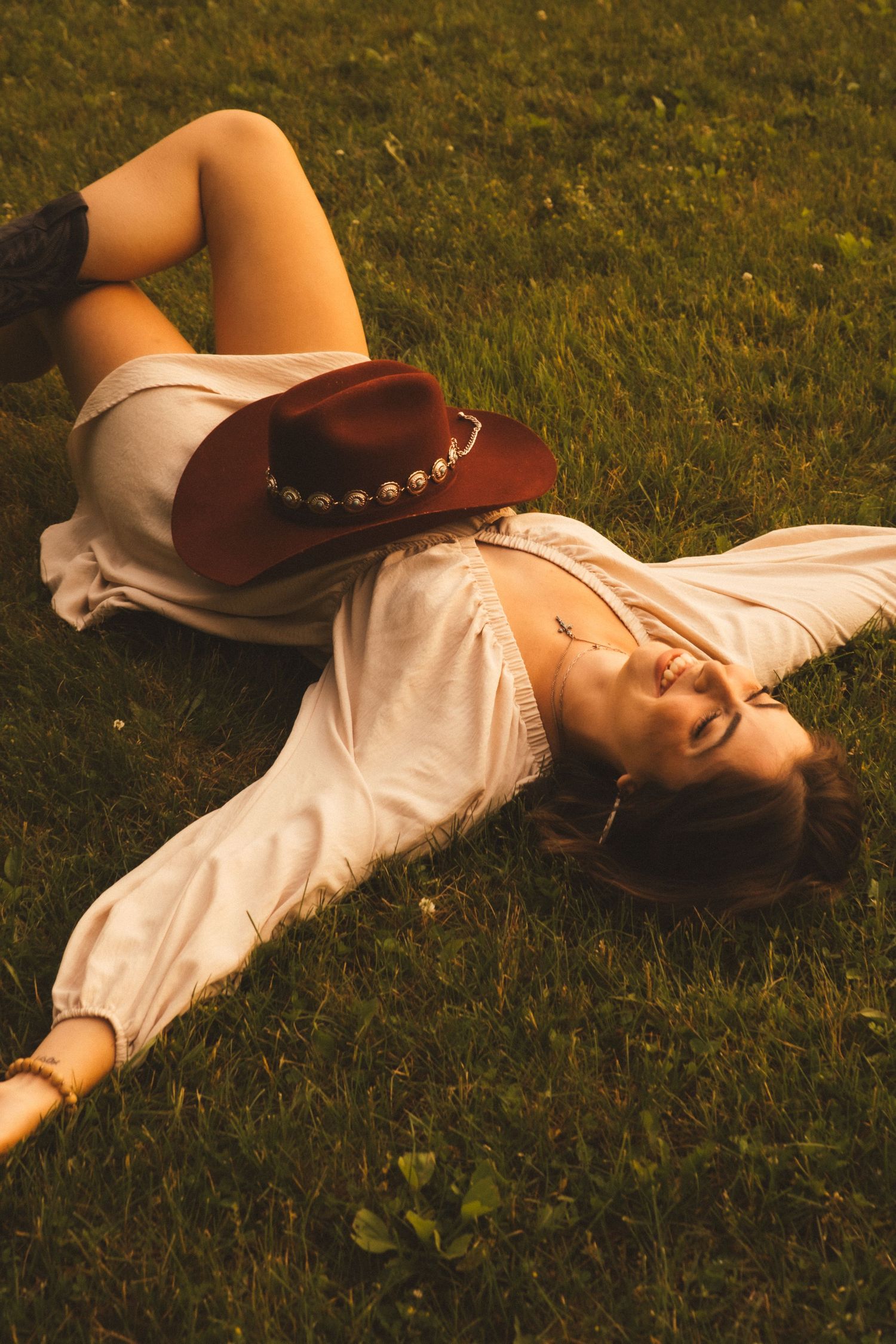 A person in a brown cowboy hat and white shirt lies peacefully on green grass in a series of connected photos.
