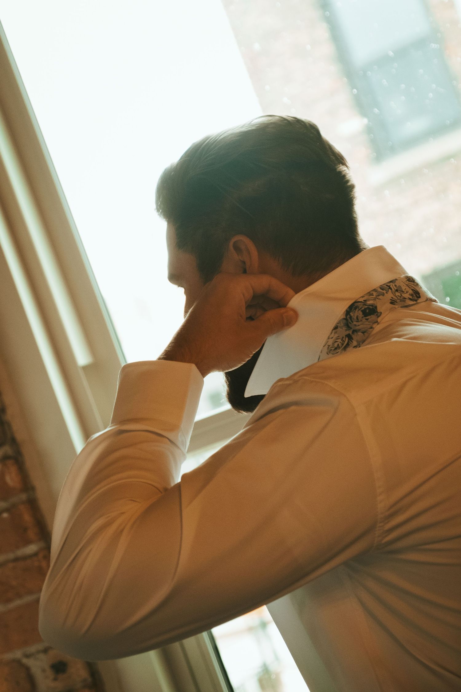 Person in white dress shirt leans forward in a sequence of five similar poses against sunlit window background.