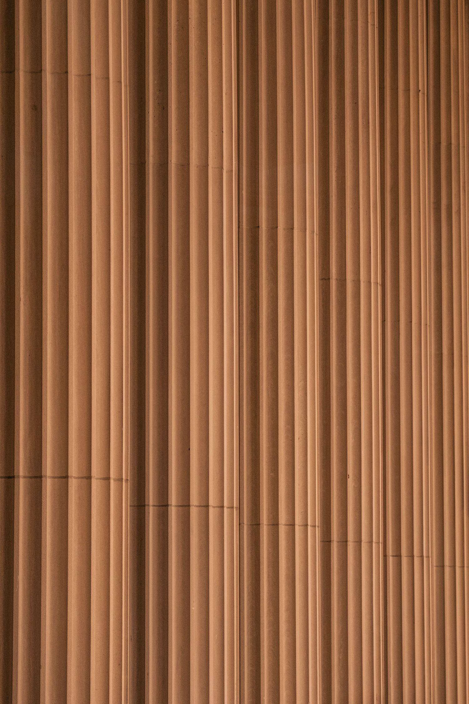 Vertical wooden slats create a modern architectural pattern with warm brown tones and parallel lines.