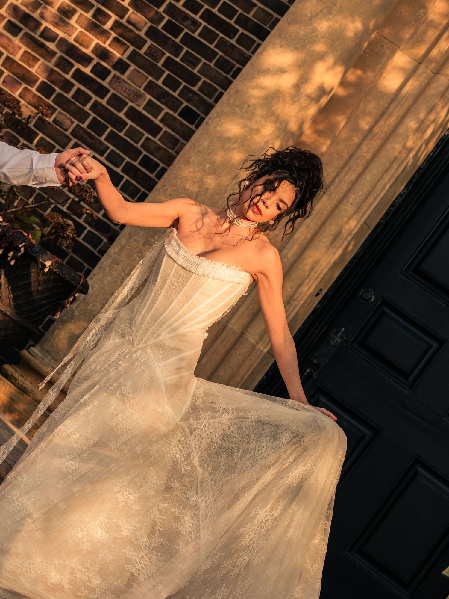 A bride in a flowing white gown twirls gracefully against a brick wall backdrop in a series of artistic wedding photos.