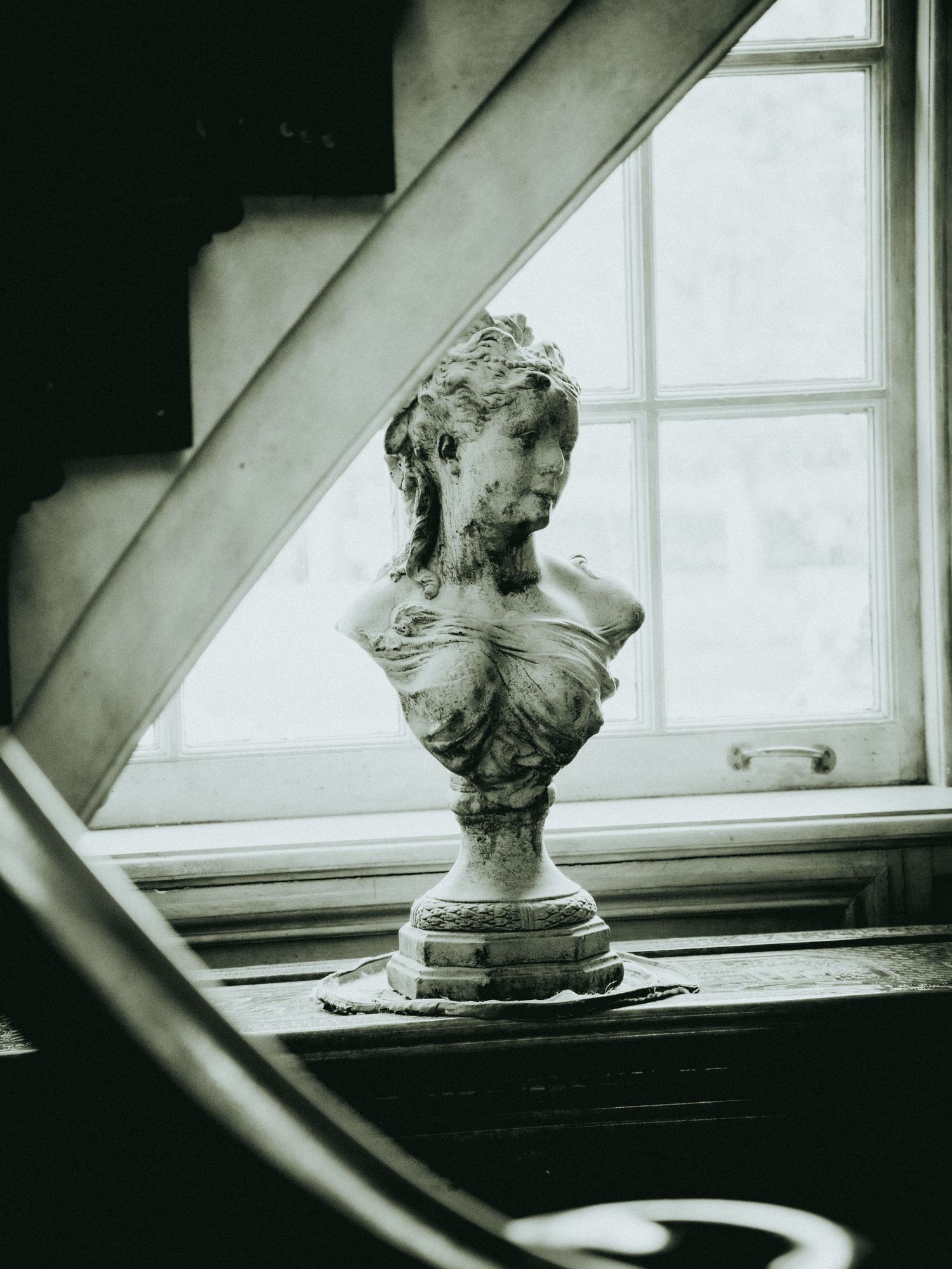 A series of black and white photographs showing a classical bust sculpture on a windowsill in varying compositions.